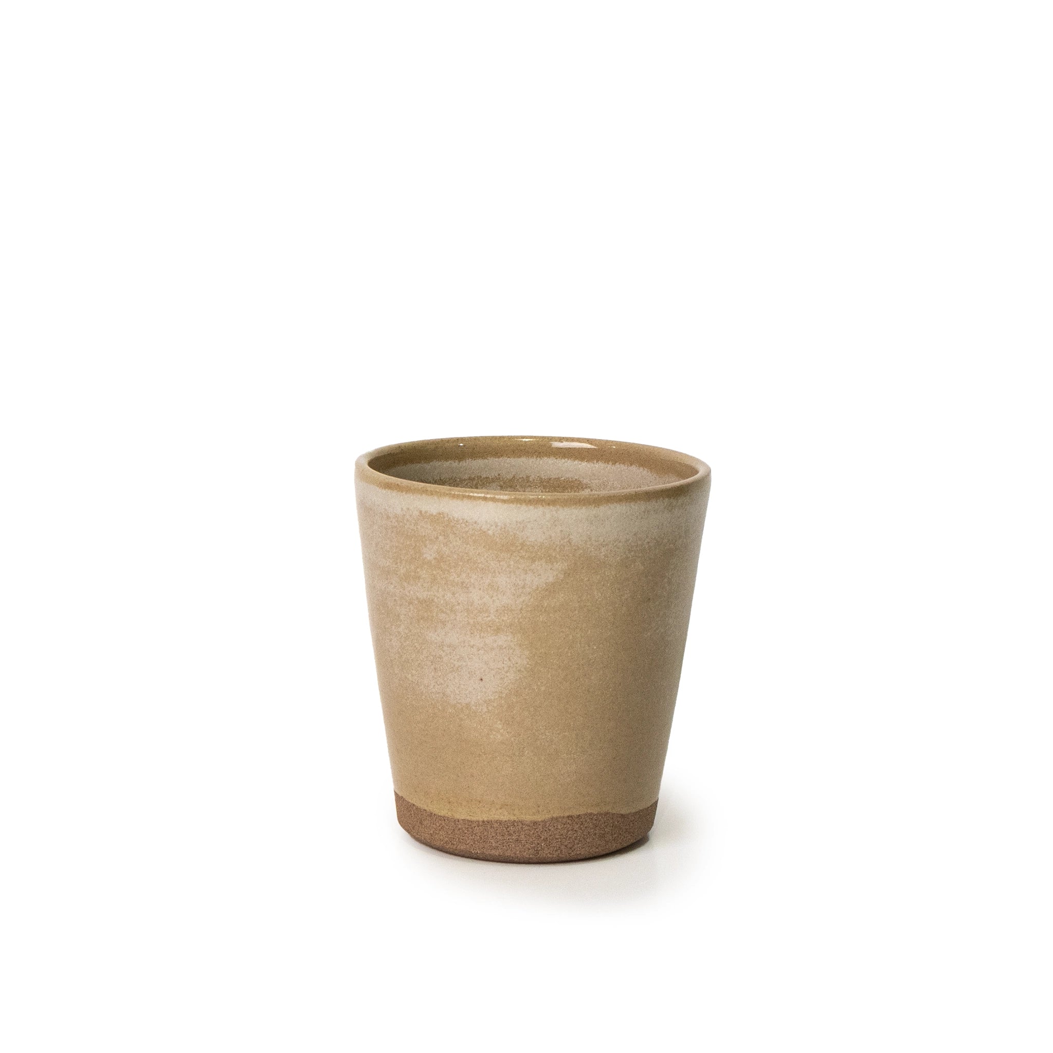 AB Ceramics Beker Toffee Satijn 20 cl: een handgemaakte, beige keramische beker van AB Ceramics, met een licht taps toelopende vorm en een mat gestructureerd oppervlak. De donkere ongeglazuurde basis vormt een aanvulling op de gladde toffee bovenkant. Afgebeeld in het midden op een witte achtergrond.