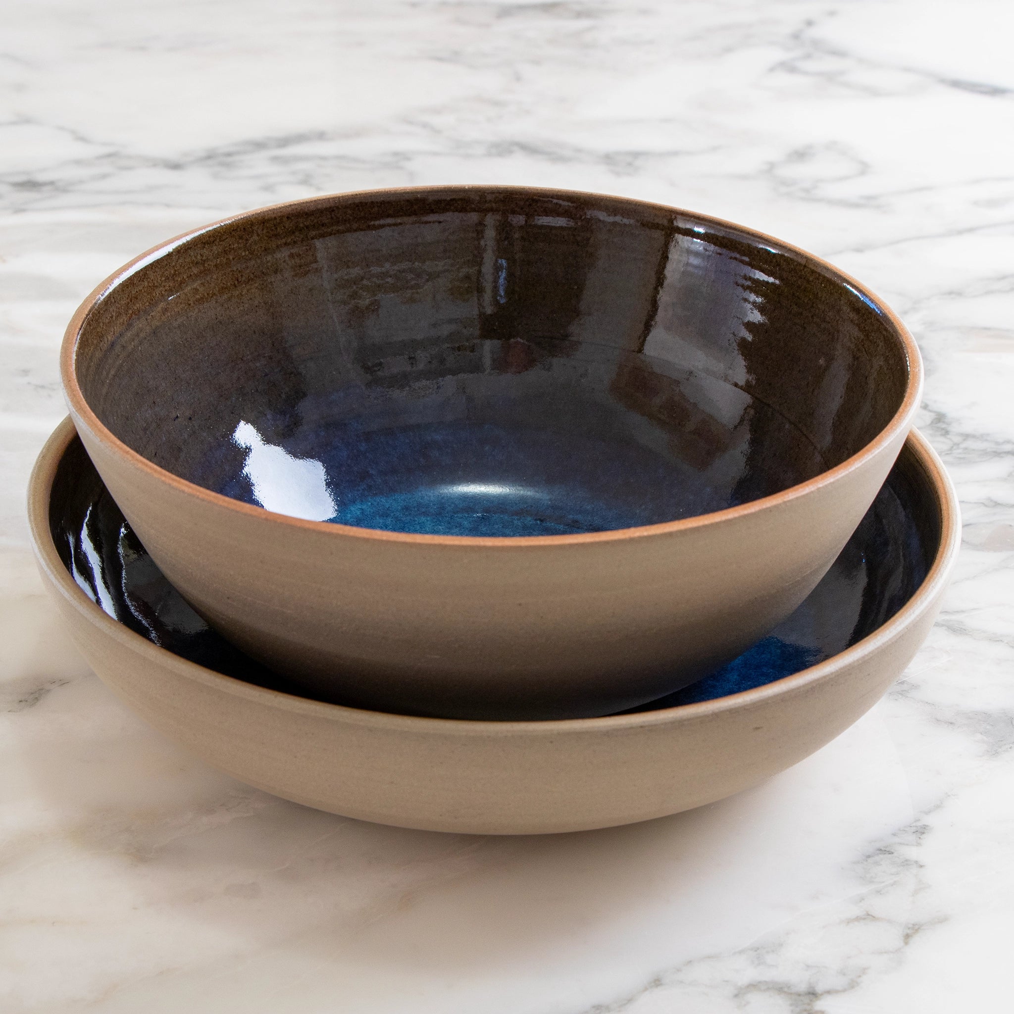 De AB Ceramics Serveerschaal Geel Blauw D25 van AB Ceramics is handgemaakt van gele steengoed klei met een beige buitenkant en glanzend donkerblauw interieur, en heeft een handgedraaide, rustieke uitstraling.