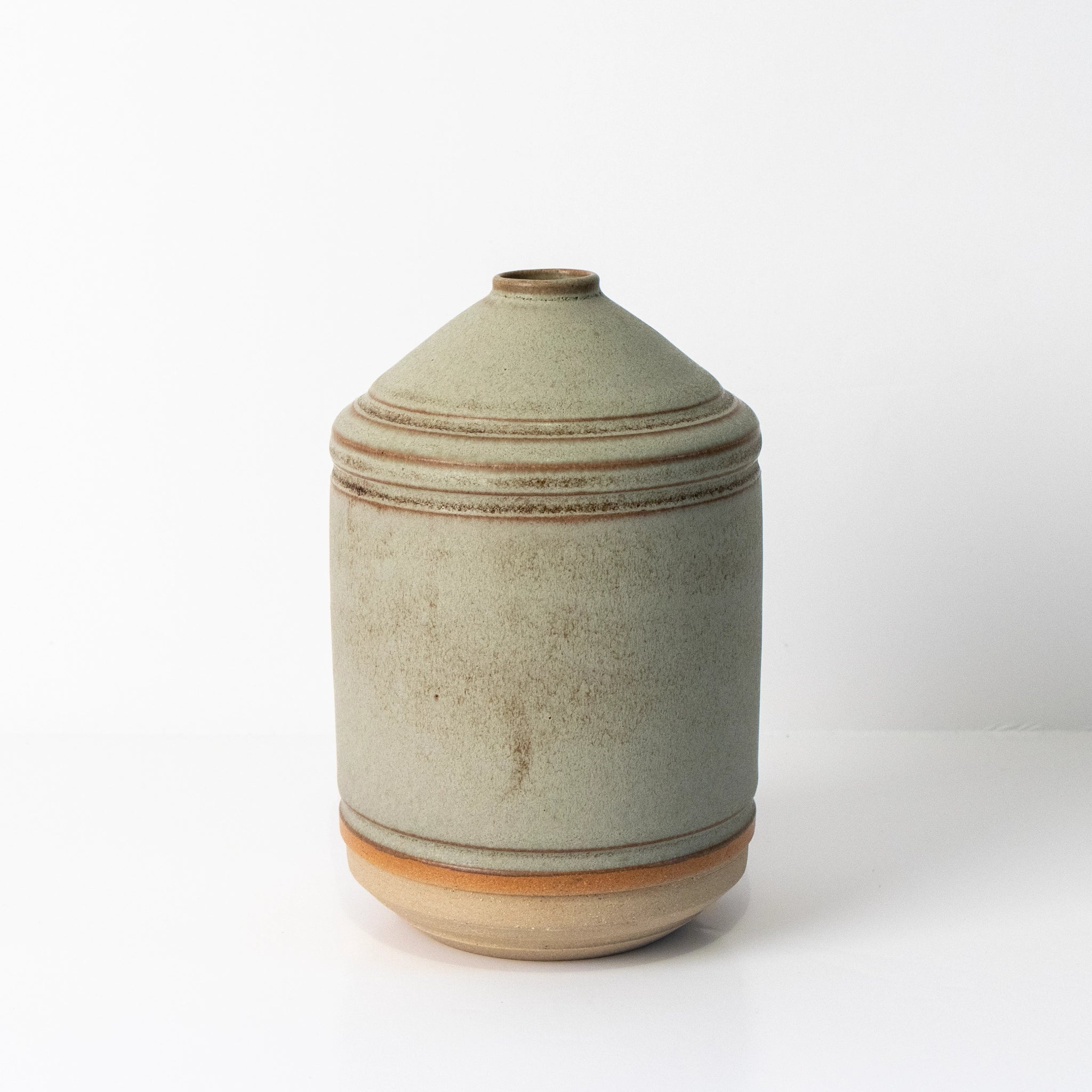 De AB Ceramics Olijfolie Fles Wit Mos 55 cl is een ronde, lichtgrijze keramieken fles met smalle opening en bruine lijnen, ideaal als stijlvolle keukenaccessoire en getoond tegen een witte achtergrond.