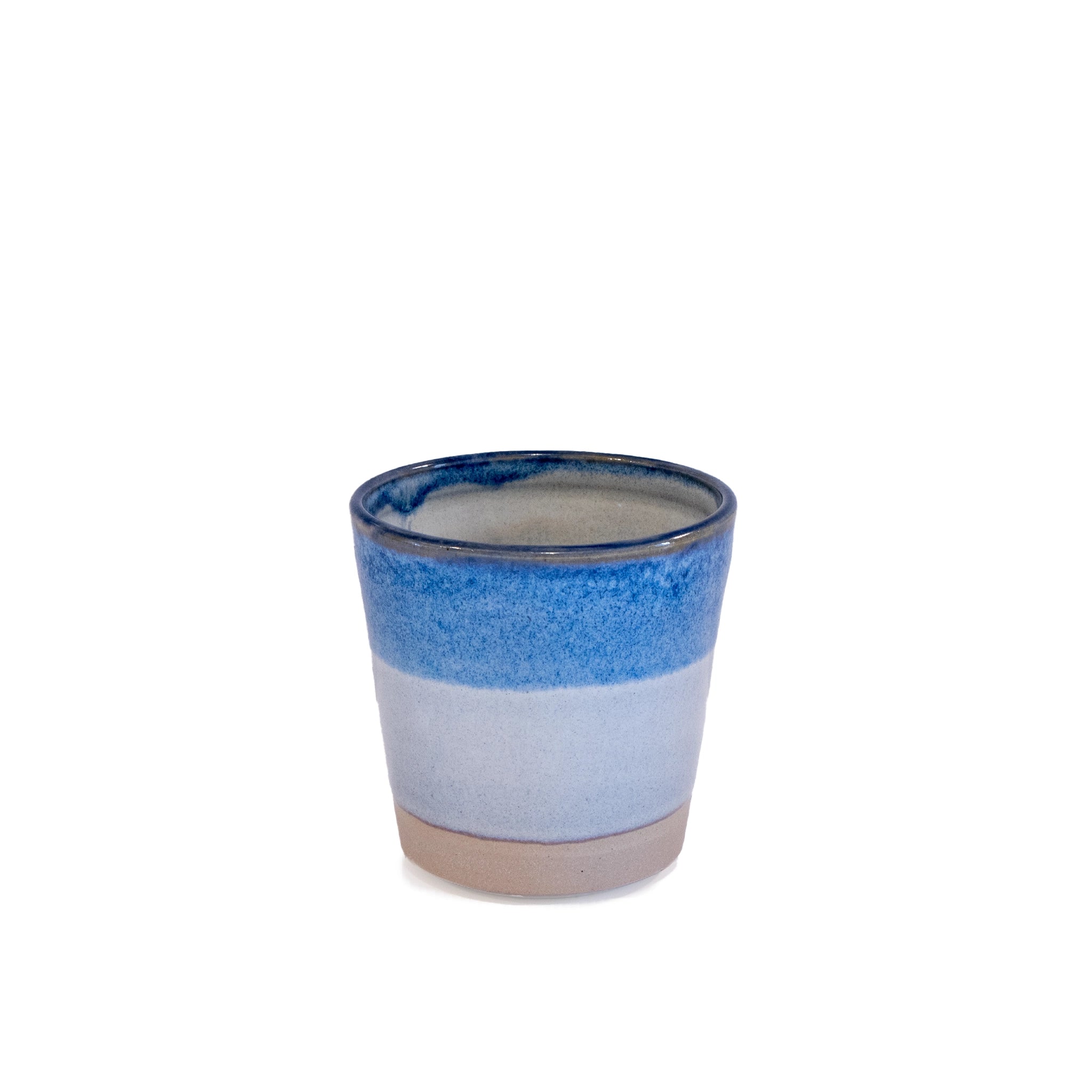 De AB Ceramics Beker Wit Opaal/Blauw 20 cl is een handgedraaid steengoed item met beige basis, lichtgrijs midden en glanzend blauwe rand. Het unieke keramiek is eenvoudig gefotografeerd tegen een witte achtergrond.
