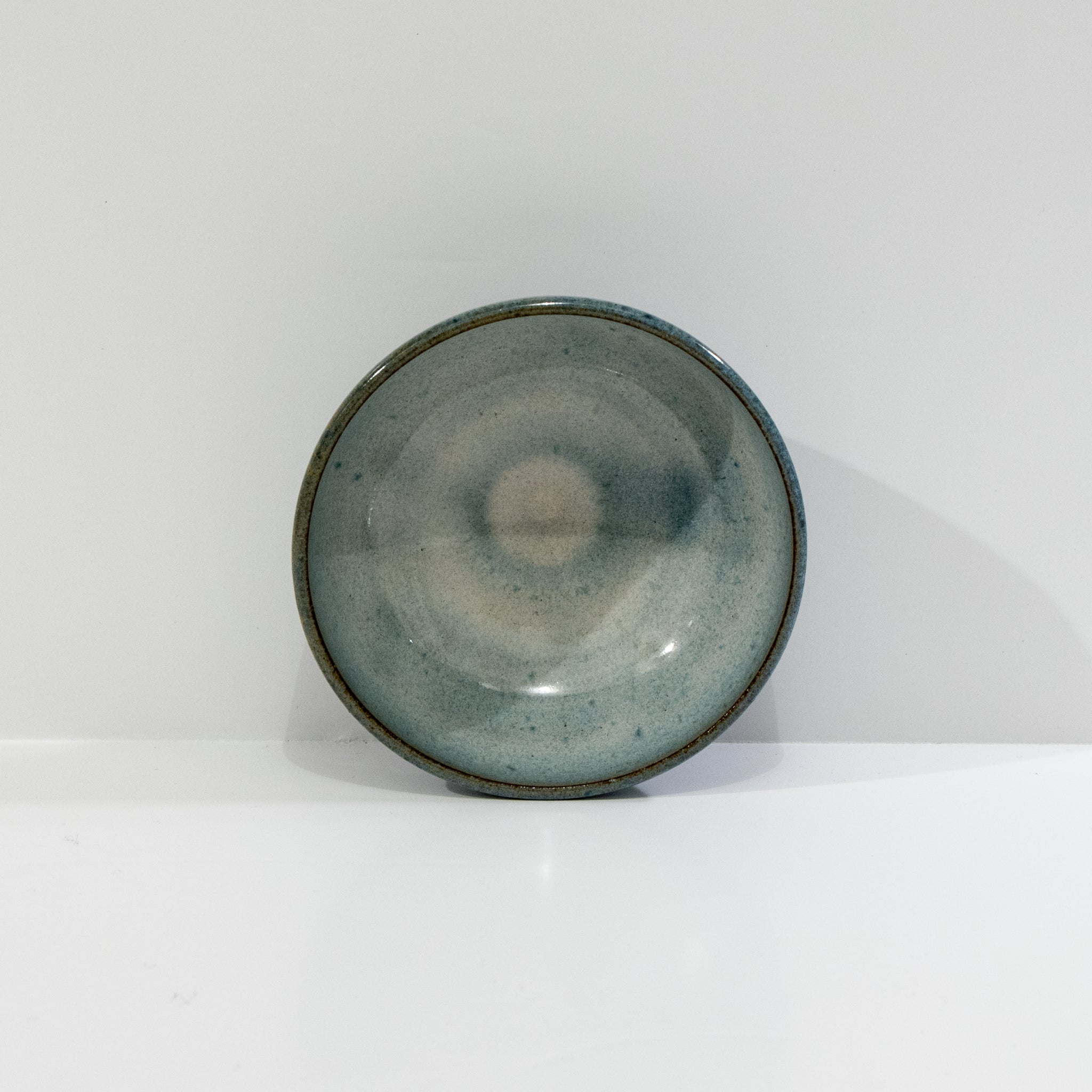 De AB Ceramics Mini Kom Rood Opaal D10,5 heeft een rood opaalglazuur en een subtiel cirkelvormig patroon in het midden, tegen een effen witte achtergrond.