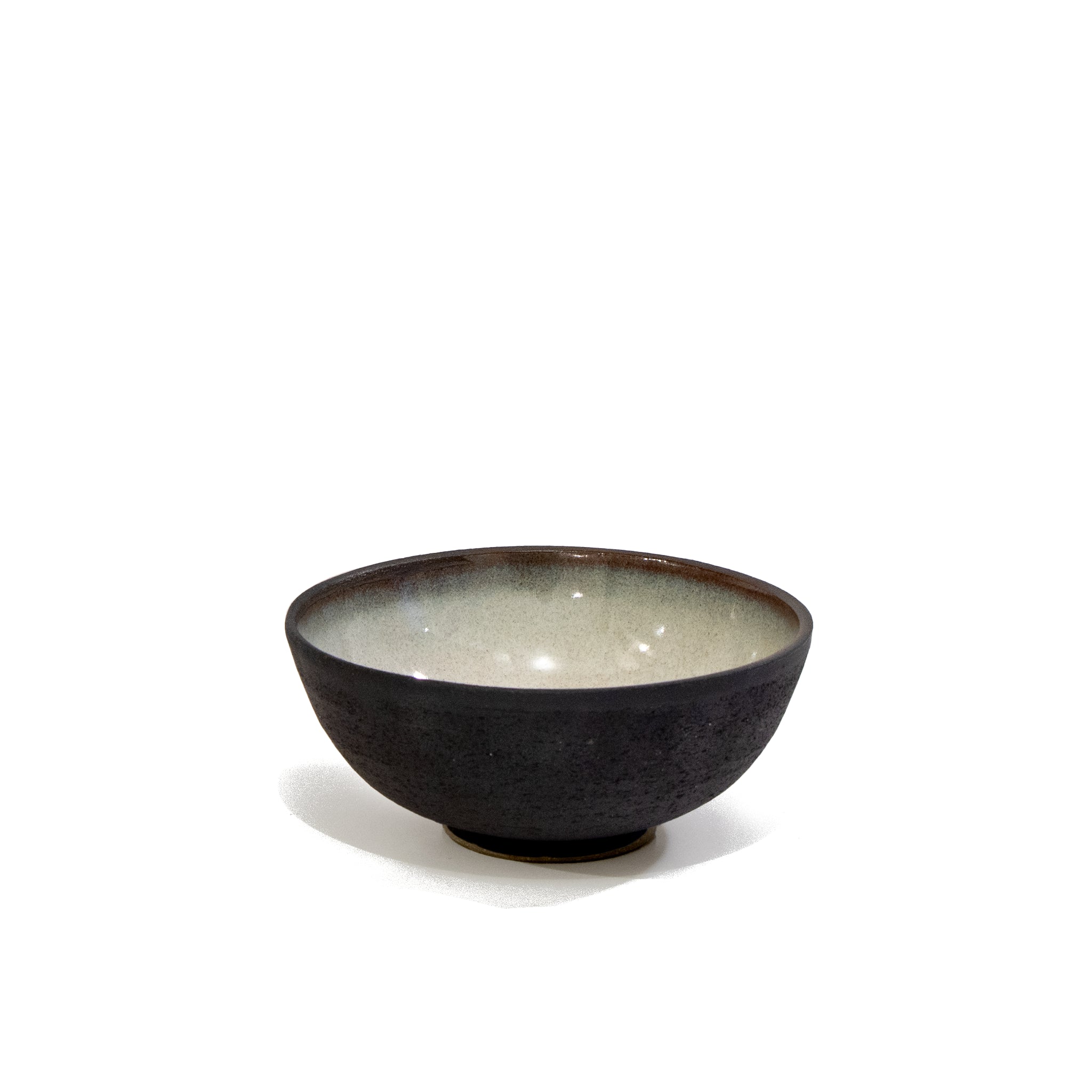 De AB Ceramics Mini Kom Zwart Opaal D10,5 is een kleine handgemaakte steengoed schaal met een donkere textuur aan de buitenkant en een gladde lichte binnenkant - ideaal voor fans van uniek servies. Van AB Ceramics, afgebeeld tegen een effen witte achtergrond.