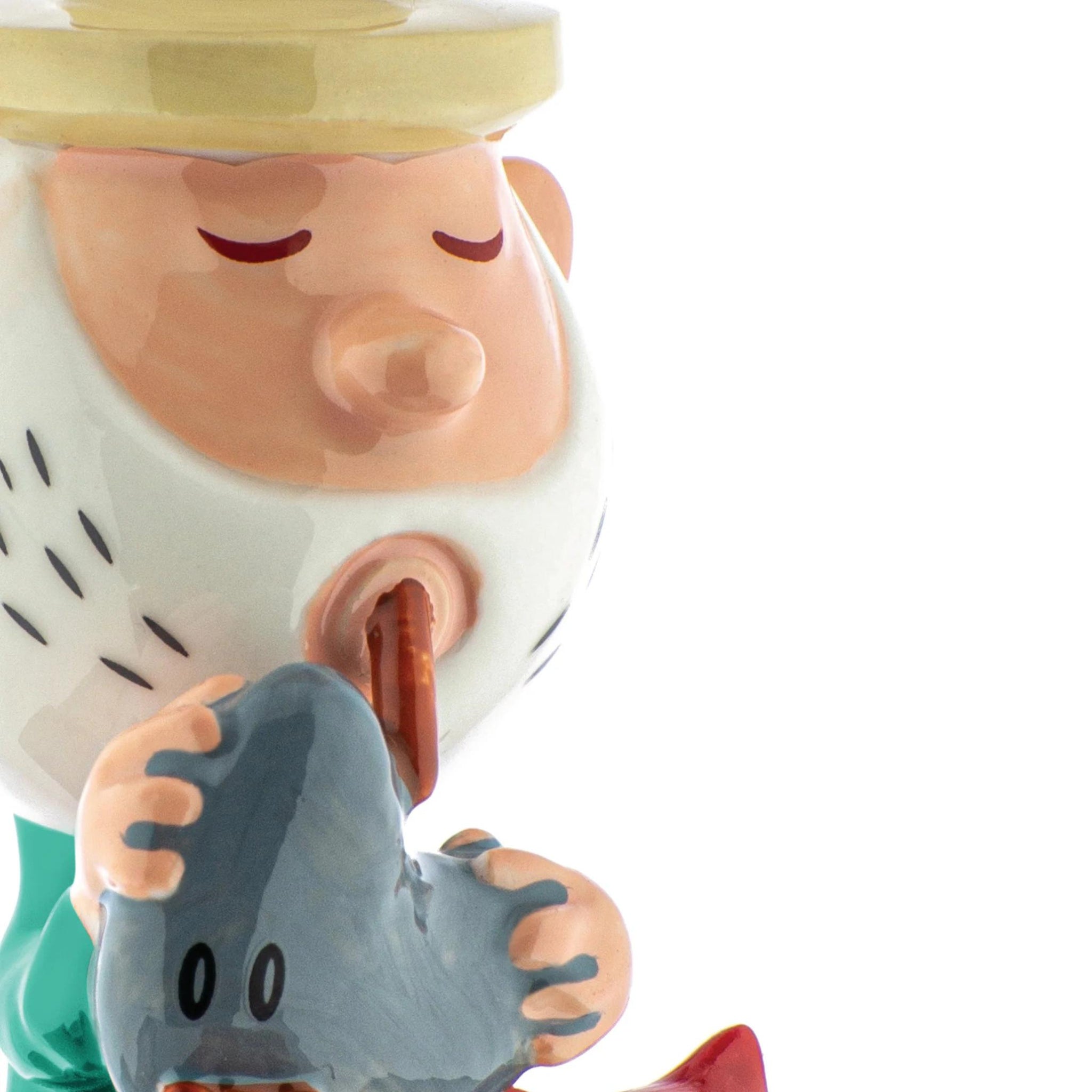 De Alessi Happy Eternity Baby Eolo De Doedelzakspeler is een keramieken beeldje van Alessi. Het stelt een bebaarde persoon voor met gesloten ogen, een bruine hoed en een grijze rots met cartoonogen, met alleen het bovenlichaam op een witte achtergrond.