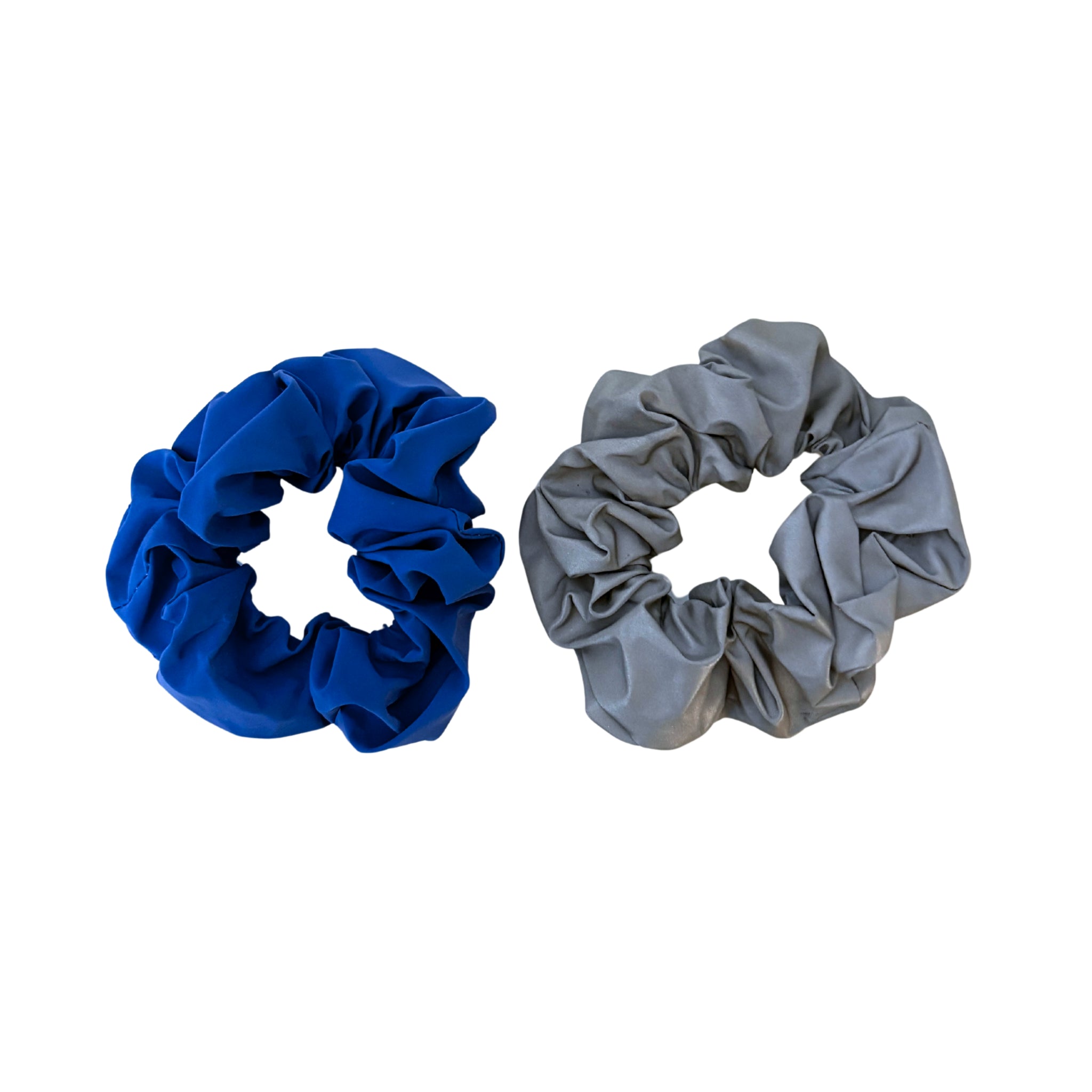 De Caro Antwerp Caro The Scrunch Club Scrunchie 2 st. bestaat uit een helderblauwe en een lichtgrijze scrunchie met gerimpelde stof; het reflecterende ontwerp zorgt voor extra zichtbaarheid, waardoor ze praktische en stijlvolle fietsaccessoires zijn.