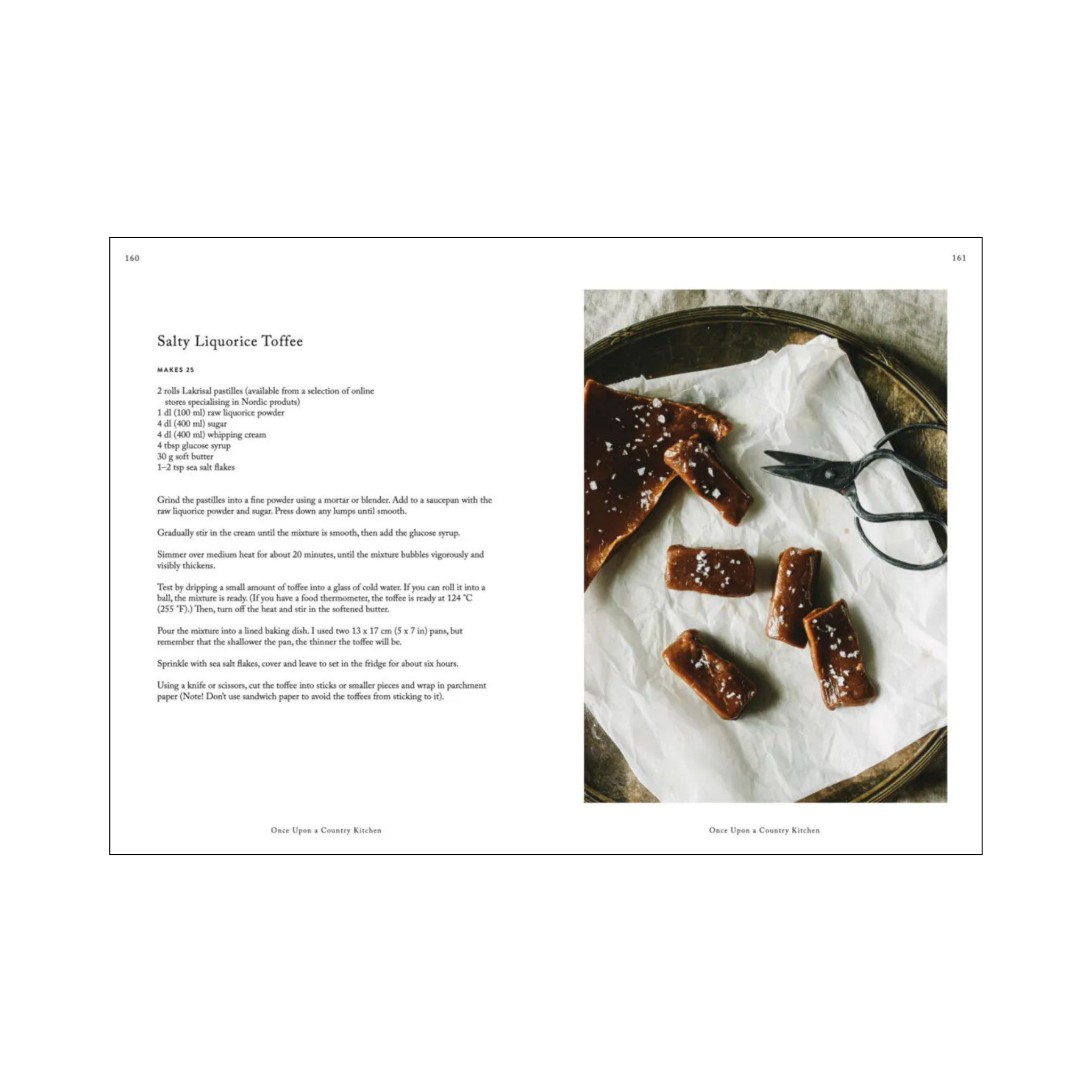Een open Cozy Publishing Once Upon A Country Kitchen Kookboek toont een recept voor zoute zoethouttoffee, terwijl de andere pagina toffee toont op een metalen dienblad met een vintage schaar - een nostalgische boerderij-charme van Cozy Publishing.