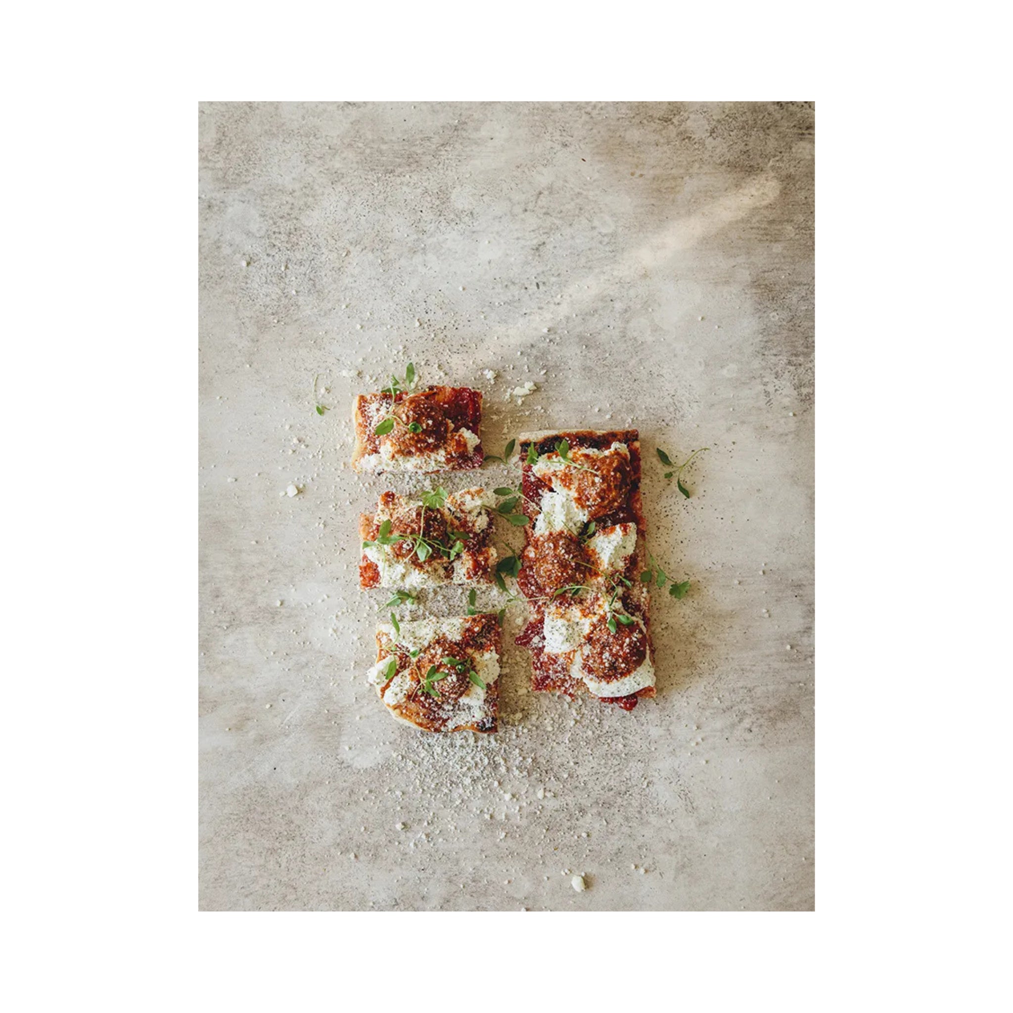 Zes vierkante plakken pizza, belegd met tomatensaus, kaas, parmezaan en kruiden, worden op een licht oppervlak uitgestald - net als de recepten in het Passione Pizza Kookboek van Cozy Publishing.