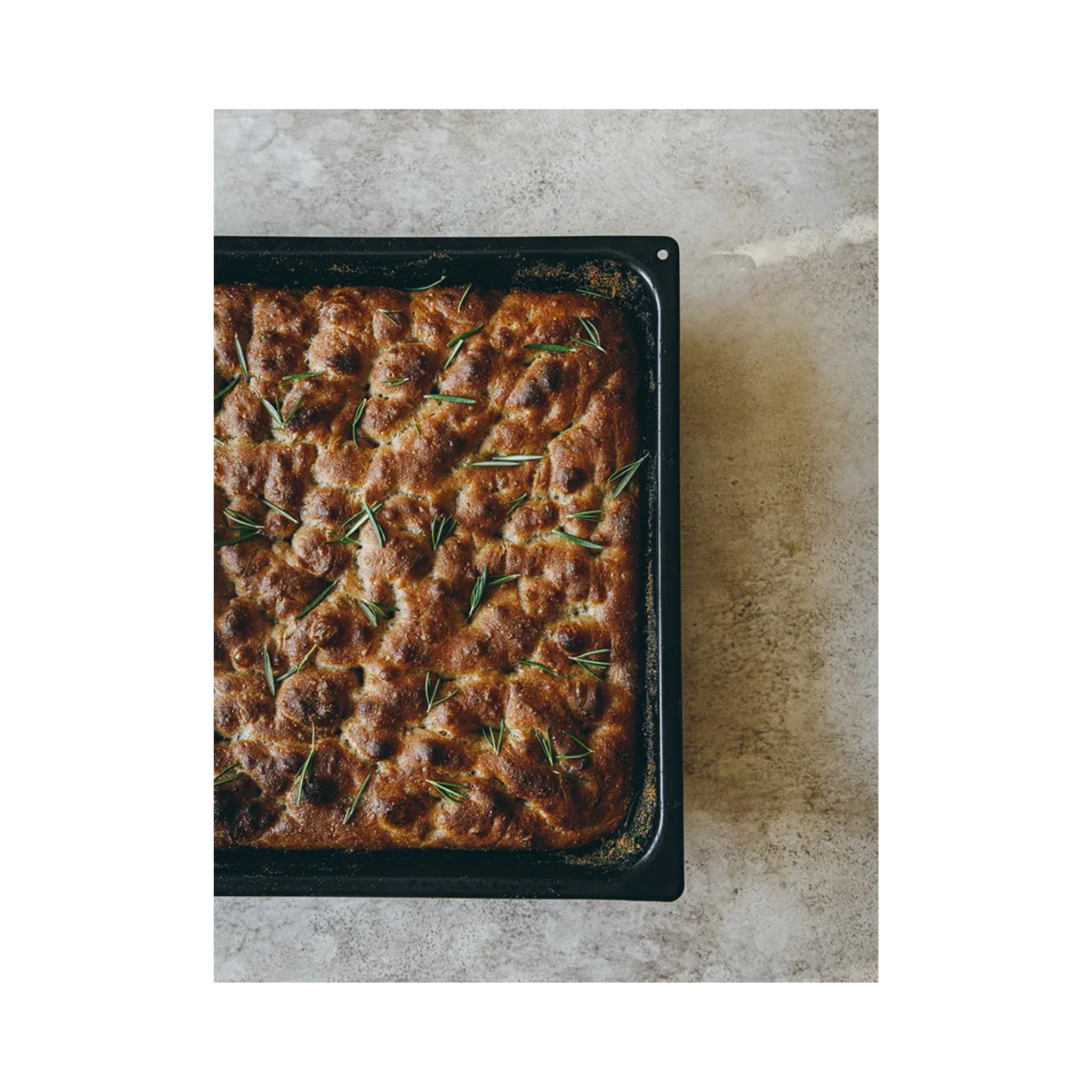 Een close-up van goudbruin focacciabrood op een dienblad, perfecte inspiratie voor zelfgemaakte pizza of om te combineren met het Passione Pizza Kookboek van Cozy Publishing.