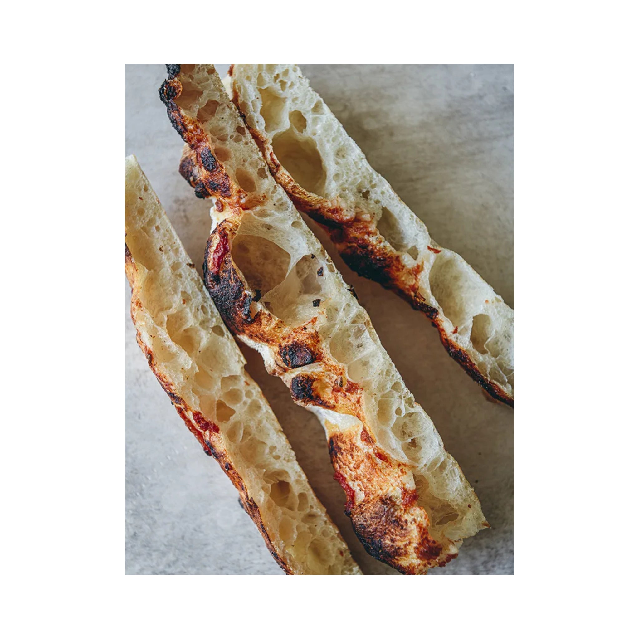 Drie sneetjes rustiek, luchtig brood met een gouden korst zijn afgebeeld - de perfecte inspiratie voor zelfgemaakte pizza's of voor iedereen die door het Passione Pizza Kookboek van Cozy Publishing bladert.