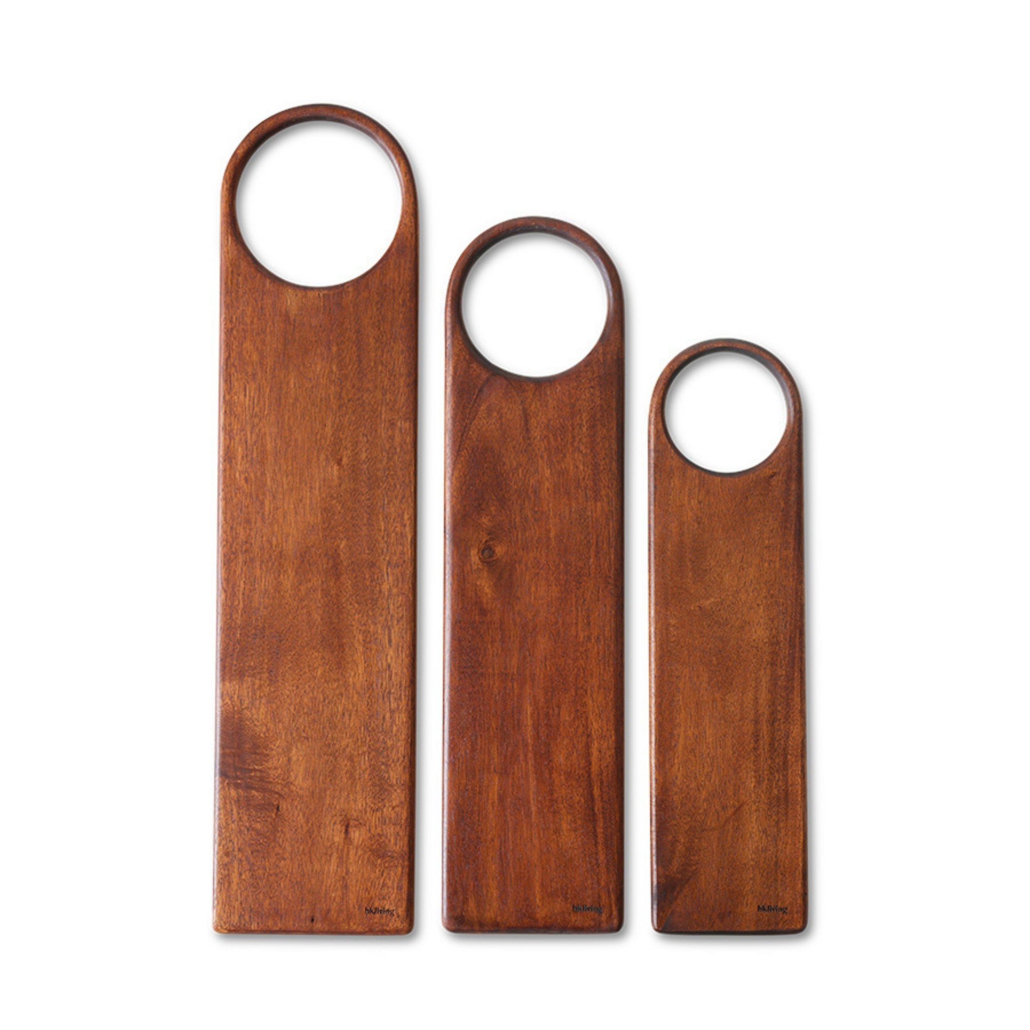 Drie HK Living Acacia Snijplank 60/15 snijplanken van verschillende hoogtes zijn naast elkaar geplaatst, elk met een grote ronde greepuitsparing en een gladde, gepolijste acaciahouten afwerking.