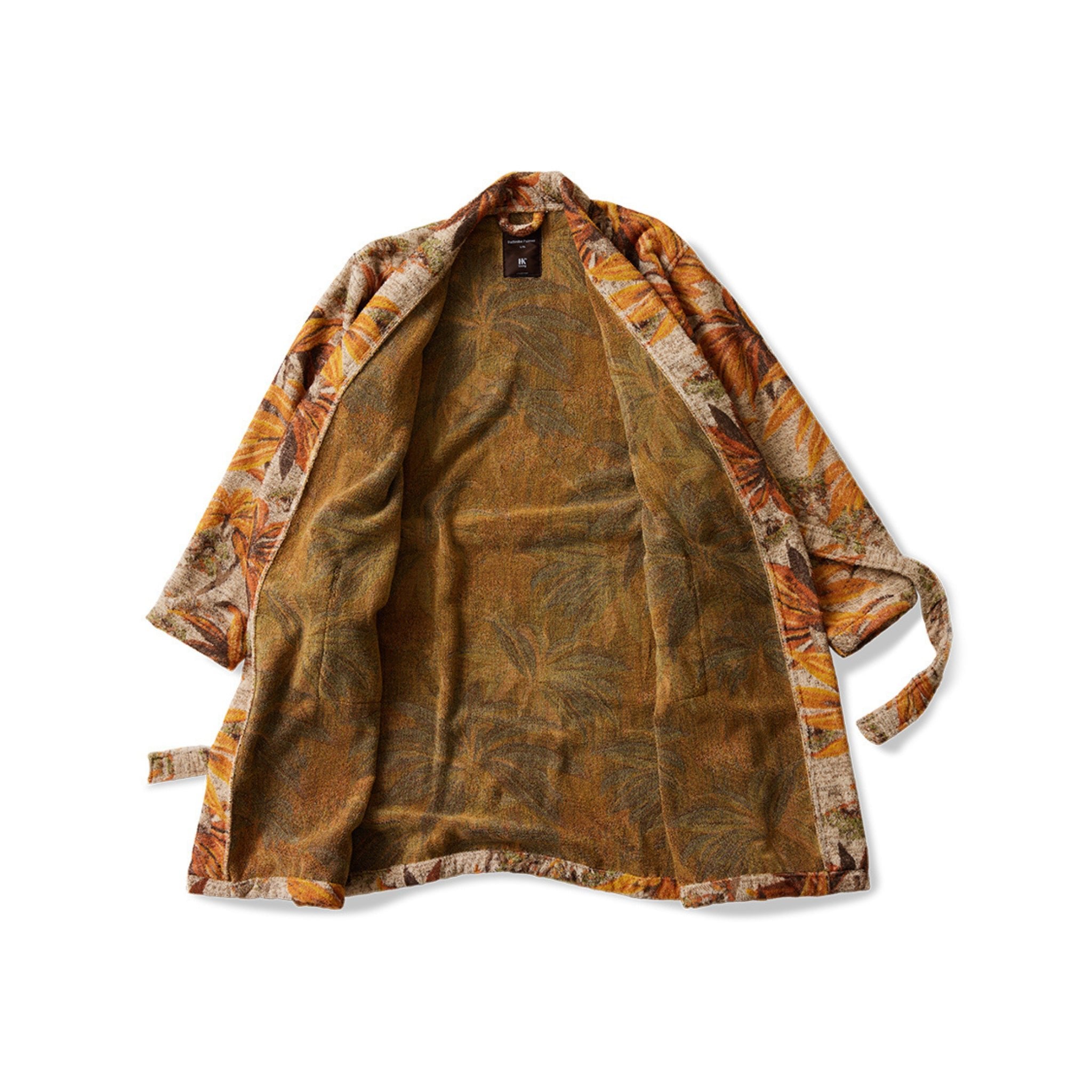 De HK Living Badjas Palmae wordt plat getoond met een losjes vastgebonden riem, heeft een aardebruin en oranje bladmotief en een zichtbare jacquard katoenen binnenvoering.