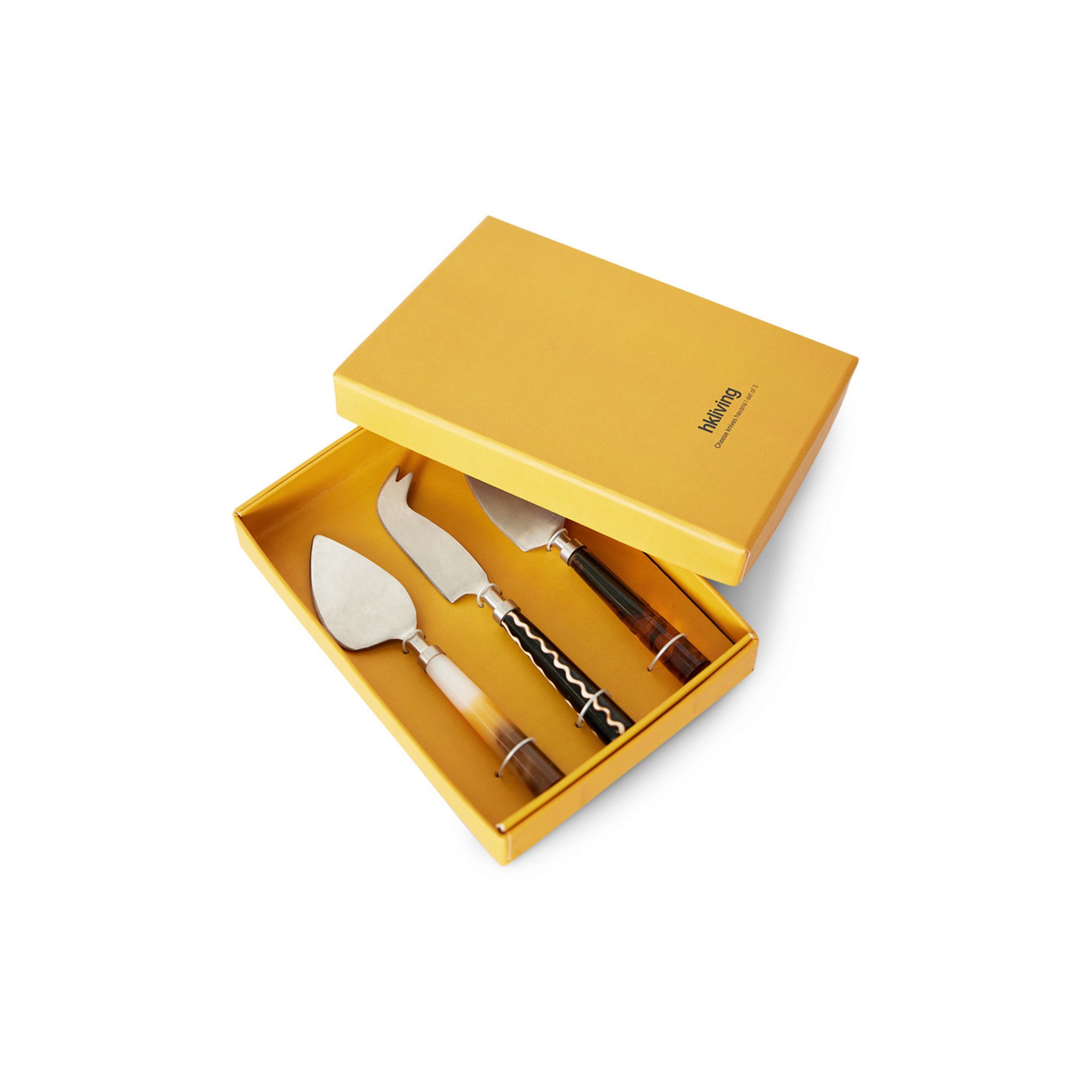 De HK Living Kaasmesjes Havana 3 st. set bestaat uit drie kaasmessen met unieke lemmeten en decoratieve handvatten in een gele HK Living doos, voorzien van geprinte tekst op het deksel en een stijlvol getailleerd interieur voor een elegante presentatie.