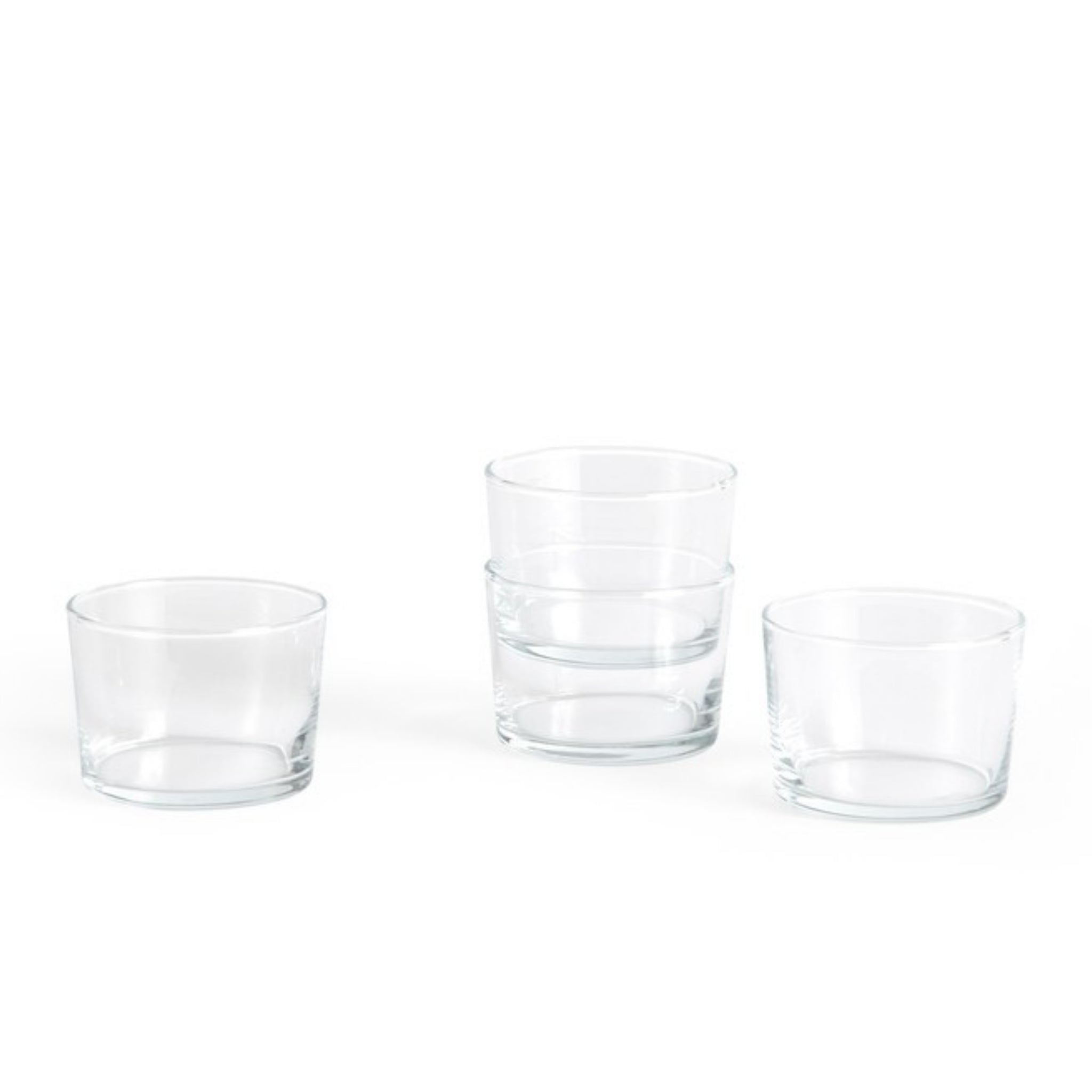 Vier Hay Glas Helder S-kopjes zijn gerangschikt op een wit oppervlak. Met een minimalistisch ontwerp is één paar ruimtebesparend gestapeld, terwijl de andere twee kleine glazen naast elkaar staan.