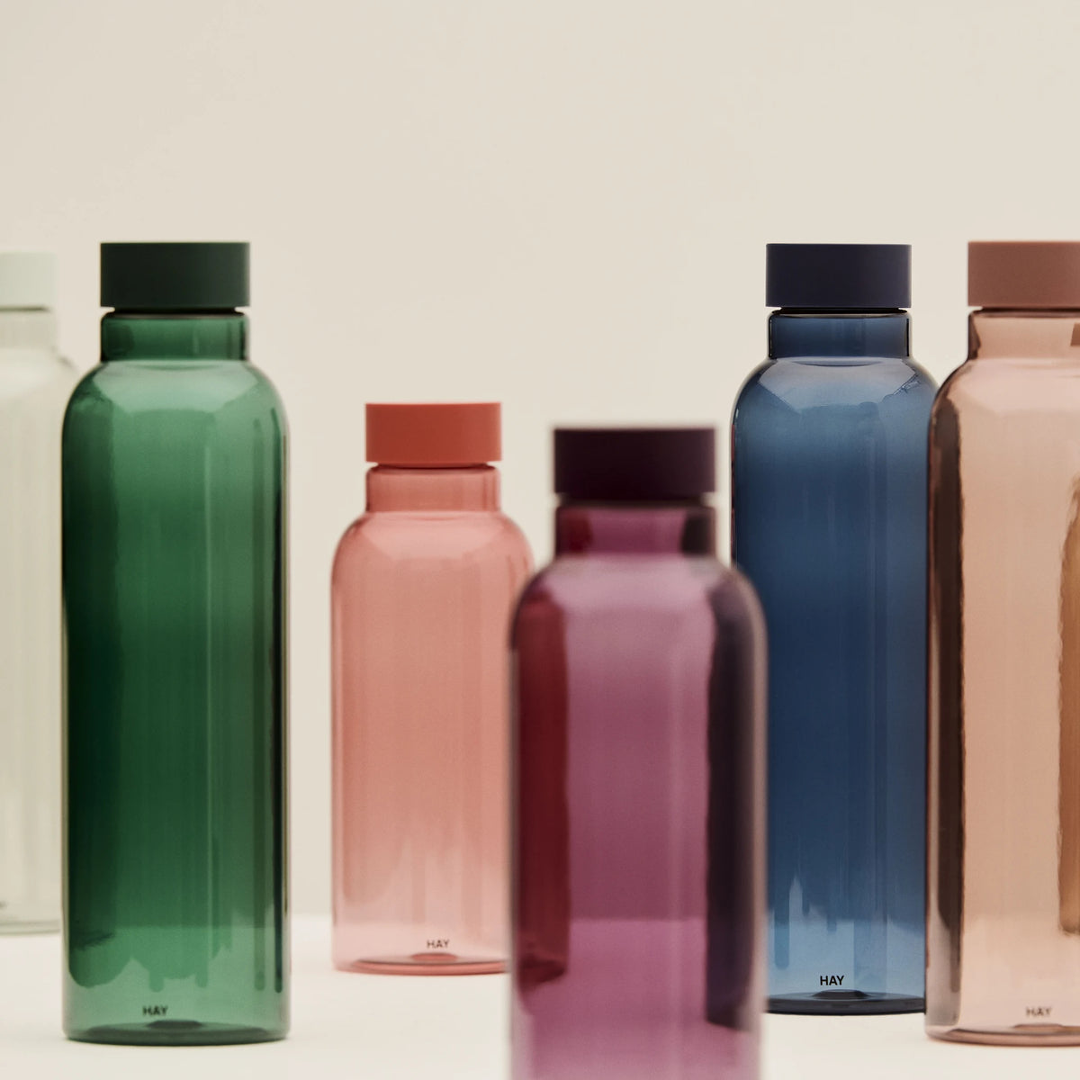 Een groep Hay Miz waterflessen in verschillende kleuren, met de Hay Miz Waterfles Rood 540 ml tussen groen en paars.