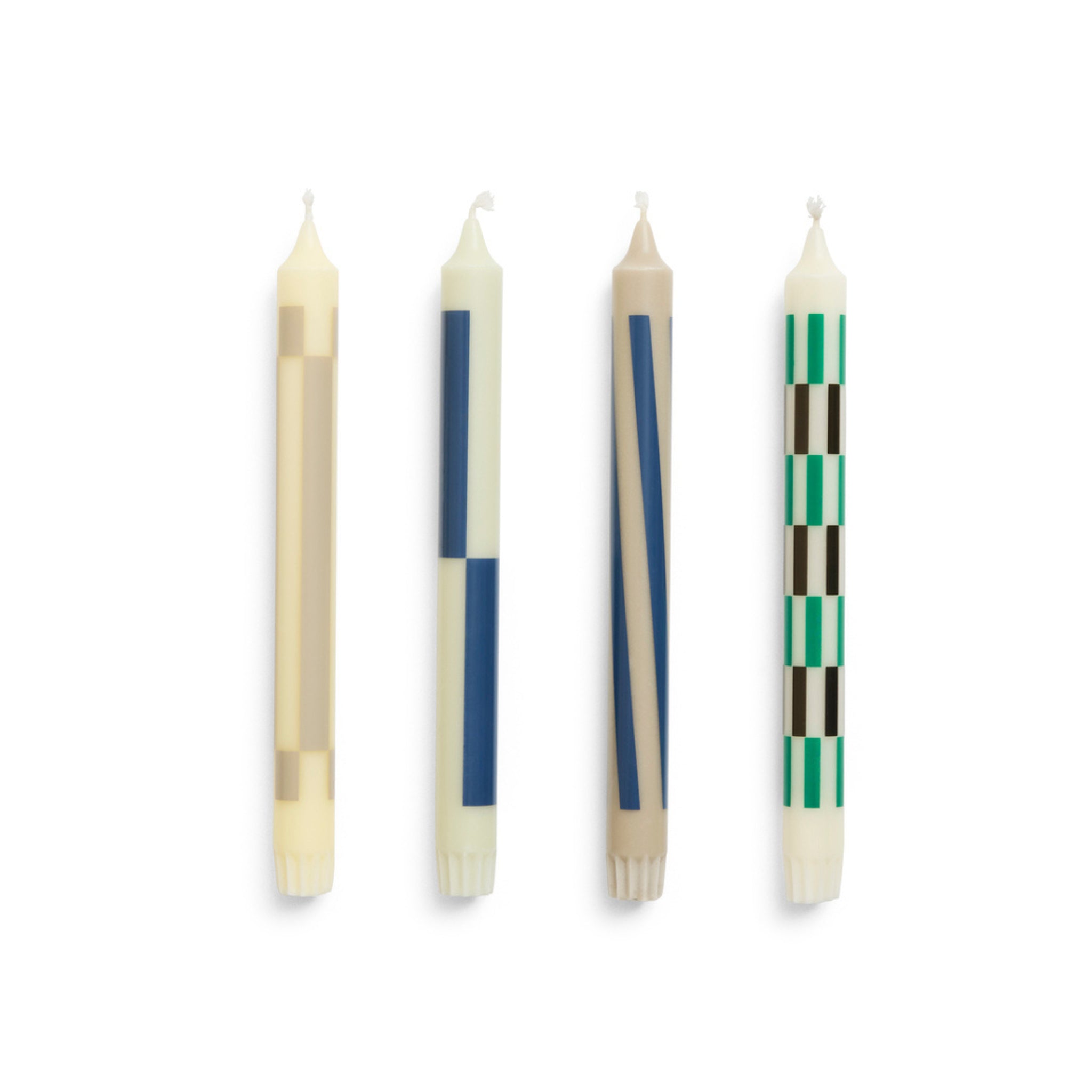 De Hay Patroon Kaarsen Crème en Donker 4 st. van Hay heeft vier rechtopstaande witte kaarsen, elk met unieke geometrische patronen in beige, blauw, bruin en groen - ideaal voor cadeauverpakkingen.
