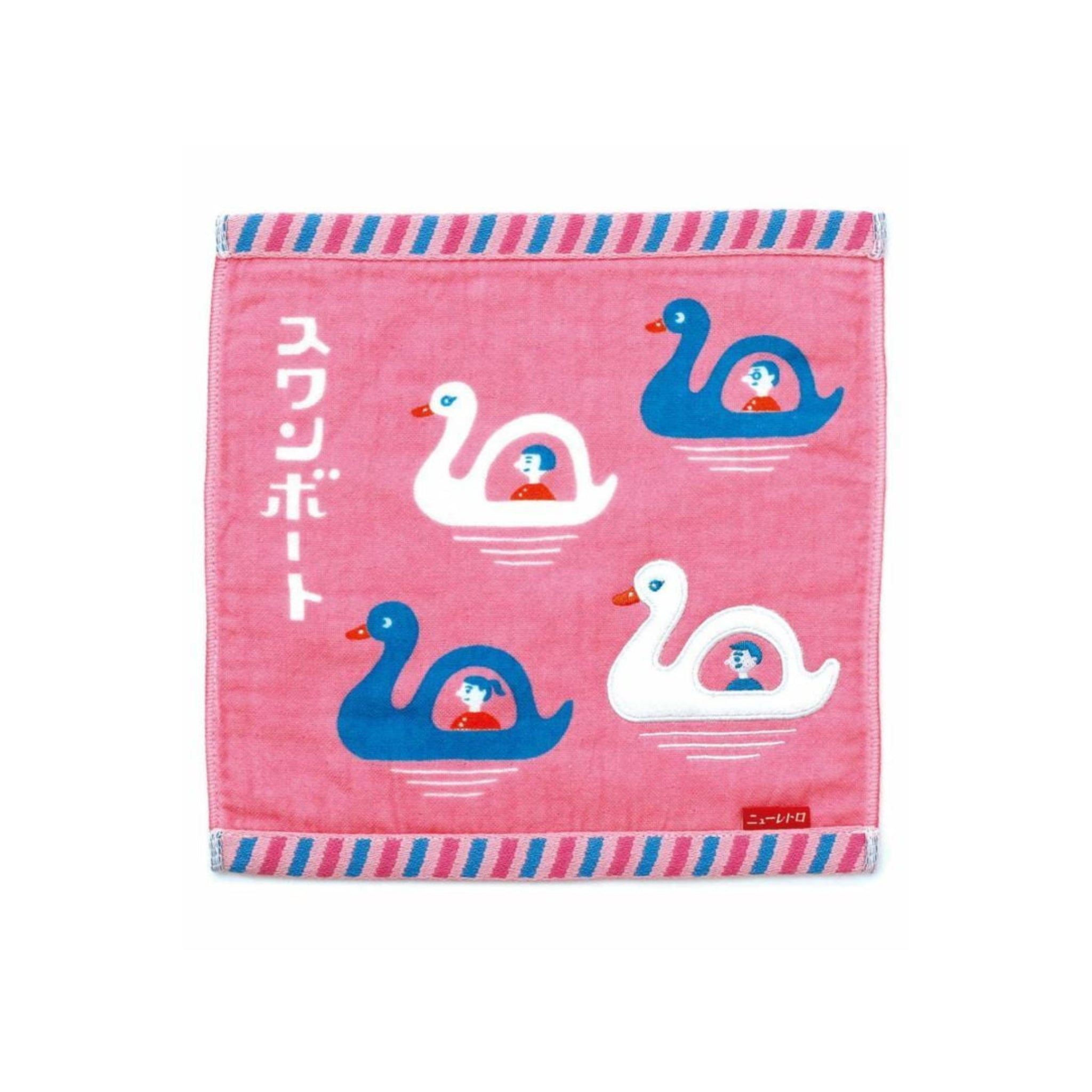 De Hightide Handdoek Zwaan Boot 25/25 van Hightide heeft blauwe en witte zwanenbootjes met ruiters op een zachtroze handdoek, geaccentueerd door Japanse tekst en een gestreepte blauwe, roze en witte rand.