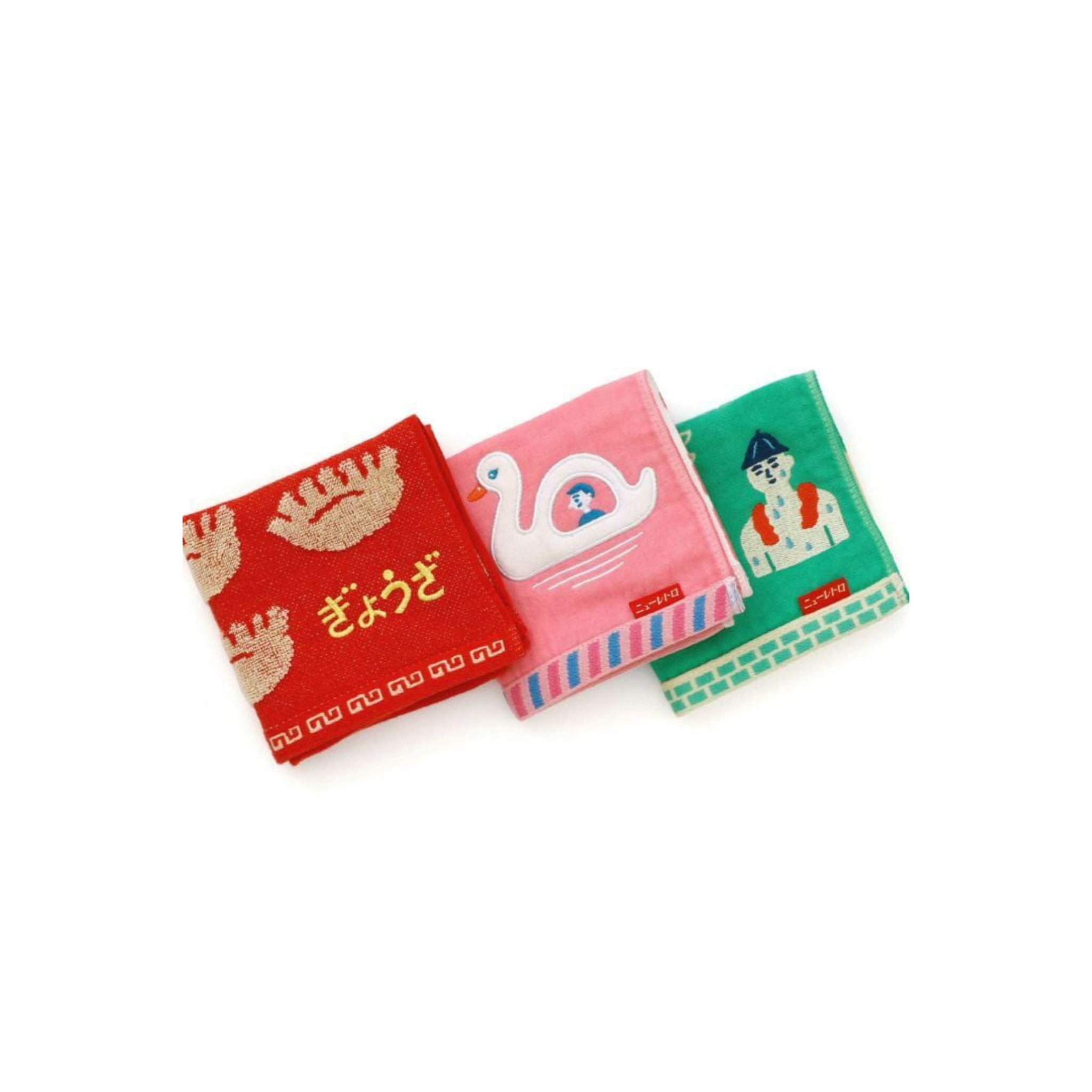 De Hightide Handdoek Zwaan Boot 25/25 set bestaat uit drie zachte, kleurrijke handdoeken: rood met garnalen en Japanse tekst, roze met een witte zwaan en groen met een zandkasteel en een persoon met een blauwe hoed.