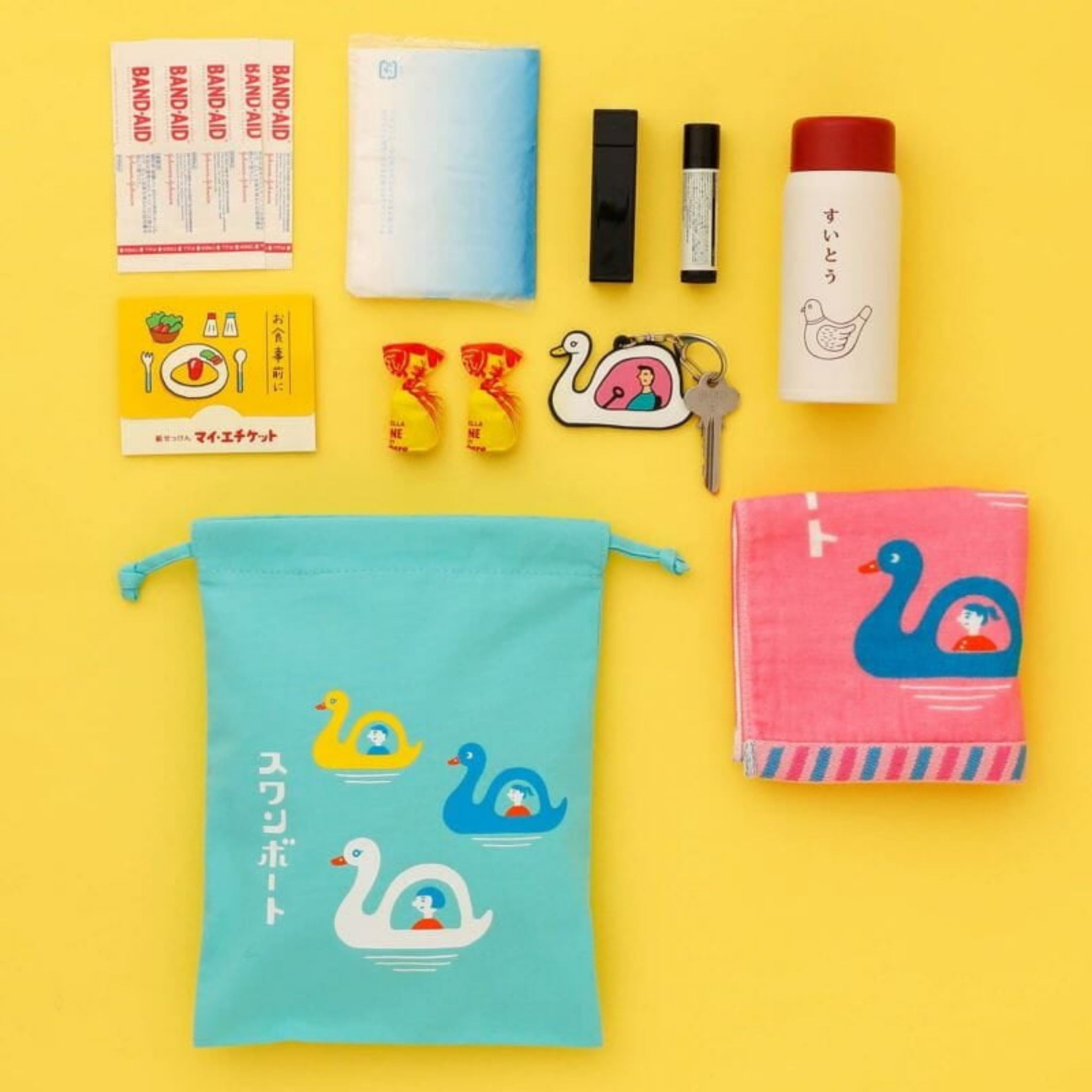 Een platte lay van alledaagse voorwerpen op een gele achtergrond, met de Hightide New Retro Katoenen Tas Zwaan Boot Medium van Hightide, plus een handdoek, tissues, verband, lippenbalsem, thermosfles, snoepjes, sleutels en decoratieve spelden.