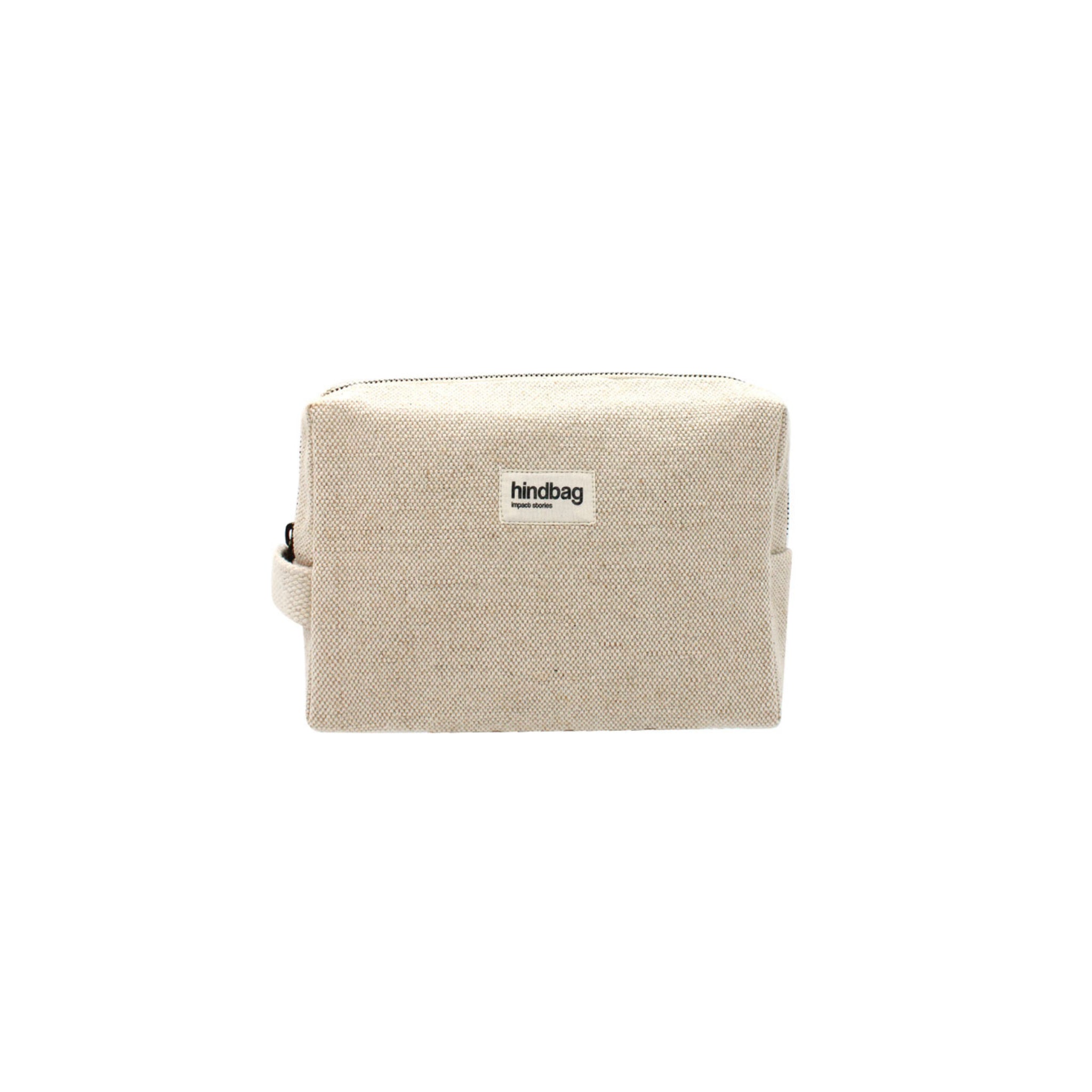 De Hindbag Leon Toilettas Jute van Hindbag is een rechthoekige beige toilettas van jute, met een handvat aan de zijkant en een klein Hindbag-label op de voorkant, tegen een effen witte achtergrond.