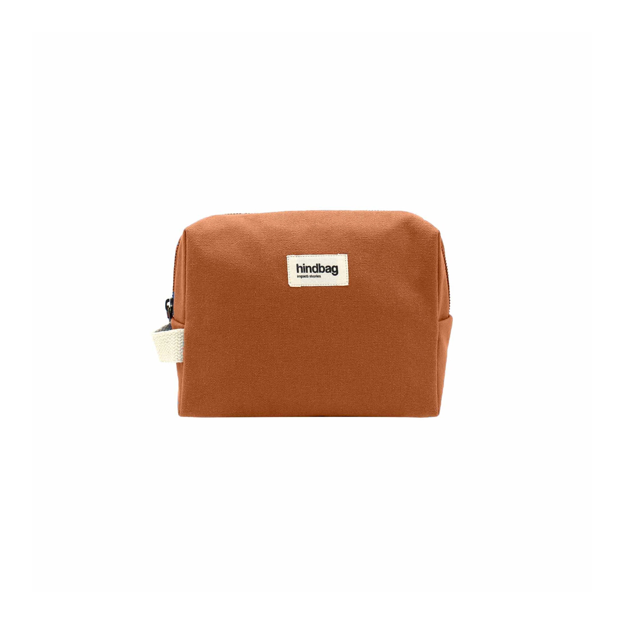 De Hindbag Leon Toilettas Siena is een rechthoekige, bruine toilettas van biologisch katoen, met een ritssluiting en een klein wit "Hindbag" label op de voorkant, tegen een effen witte achtergrond.