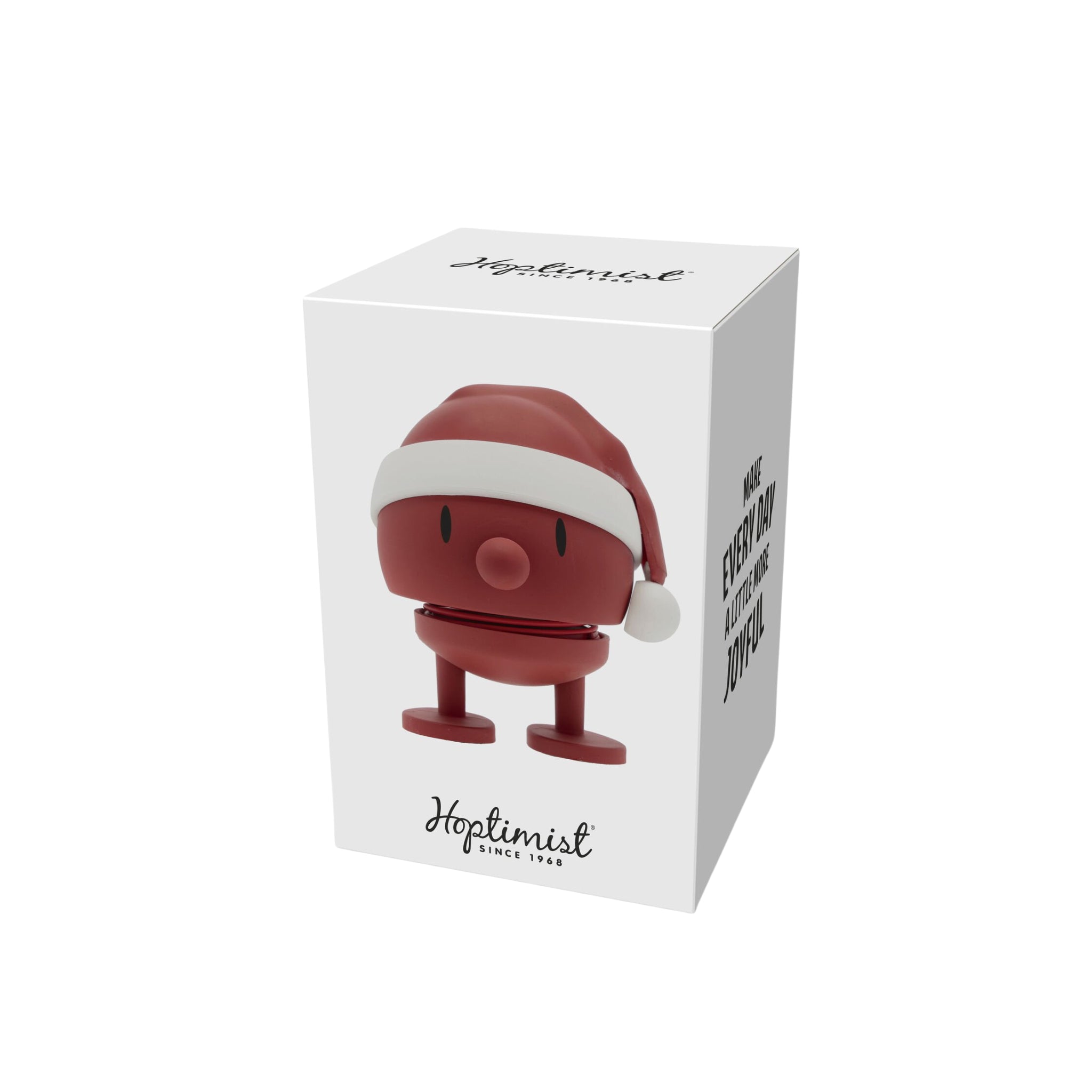 In een witte doos met het Hoptimist-logo zit de Hoptimist Soft Santa Bumble S Rood - rood, rond speelgoed met een kerstmuts en twee poten - met een Deens ontwerp en de zin MAKE EVERY DAY MORE JOYFUL.
