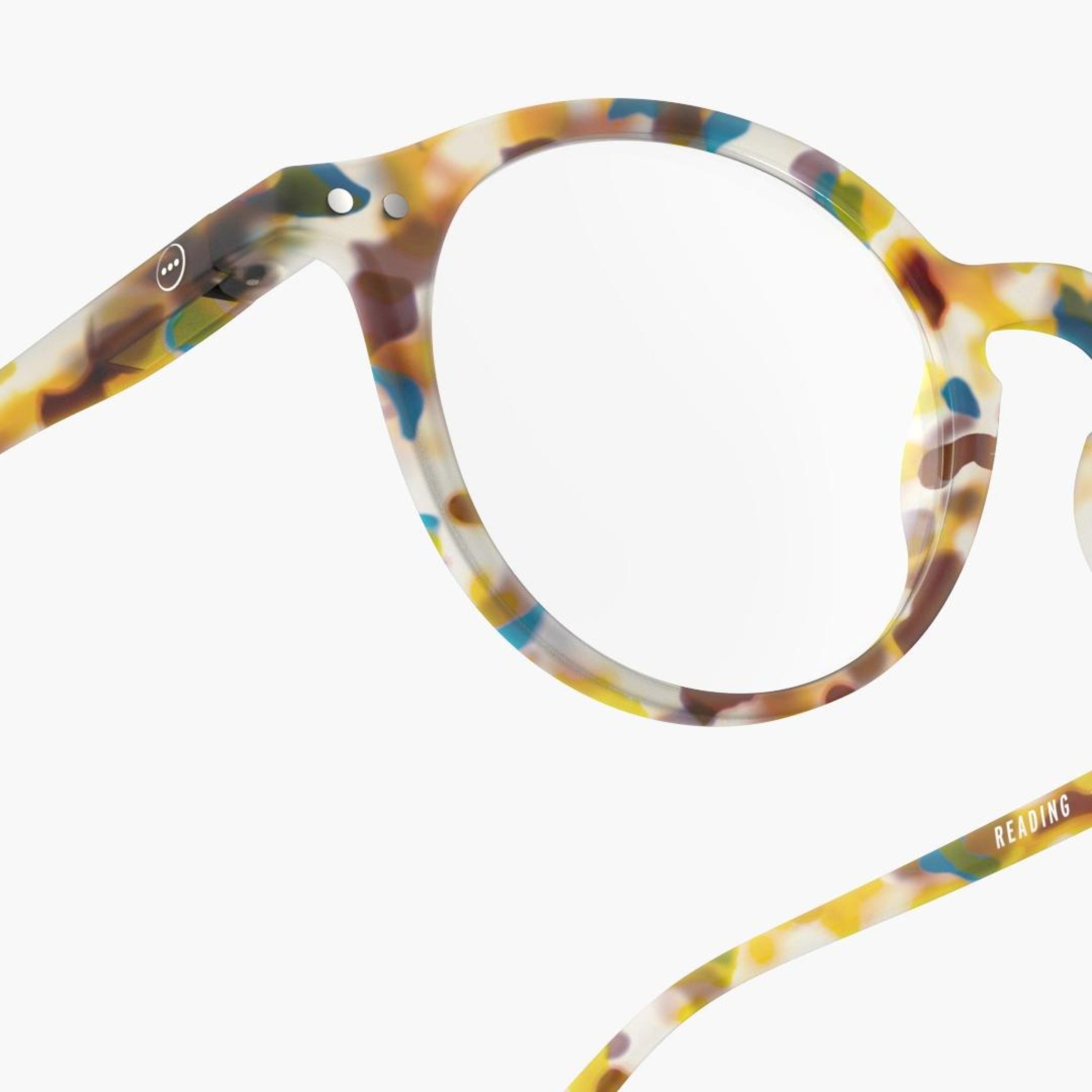 Close-up van de Izipizi Leesbril #D Blue Tortoise leesbril van Izipizi, met een stijlvol rond montuur met blauw, geel, bruin en wit gespikkeld acetaat - ideaal voor presbyopie. Weergegeven op een effen witte achtergrond.
