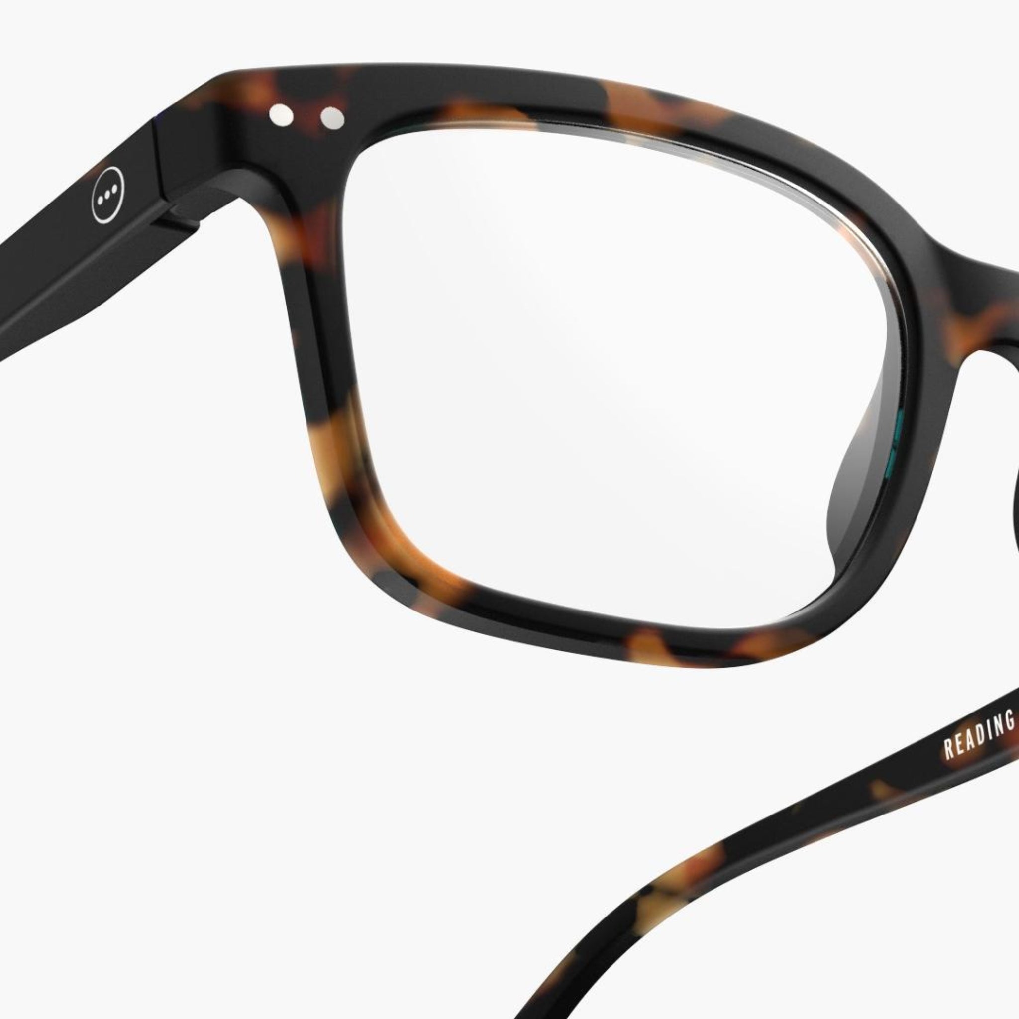 Close-up van de Izipizi Leesbril #L Tortoise leesbril van Izipizi, met een rechthoekig montuur van schildpad, met een accent op de voorkant en een deel van de arm tegen een witte achtergrond.