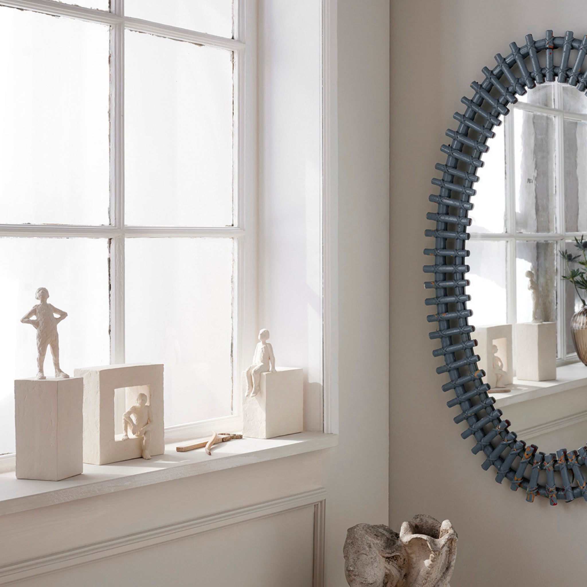 In een lichte vensterbank staat de minimalistische Kähler Astro Sterrenbeeld Sculptuur Kreeft op een bloksokkel naast een ronde spiegel in industriële stijl op een beige muur, met zacht natuurlijk licht dat de kamer vult.