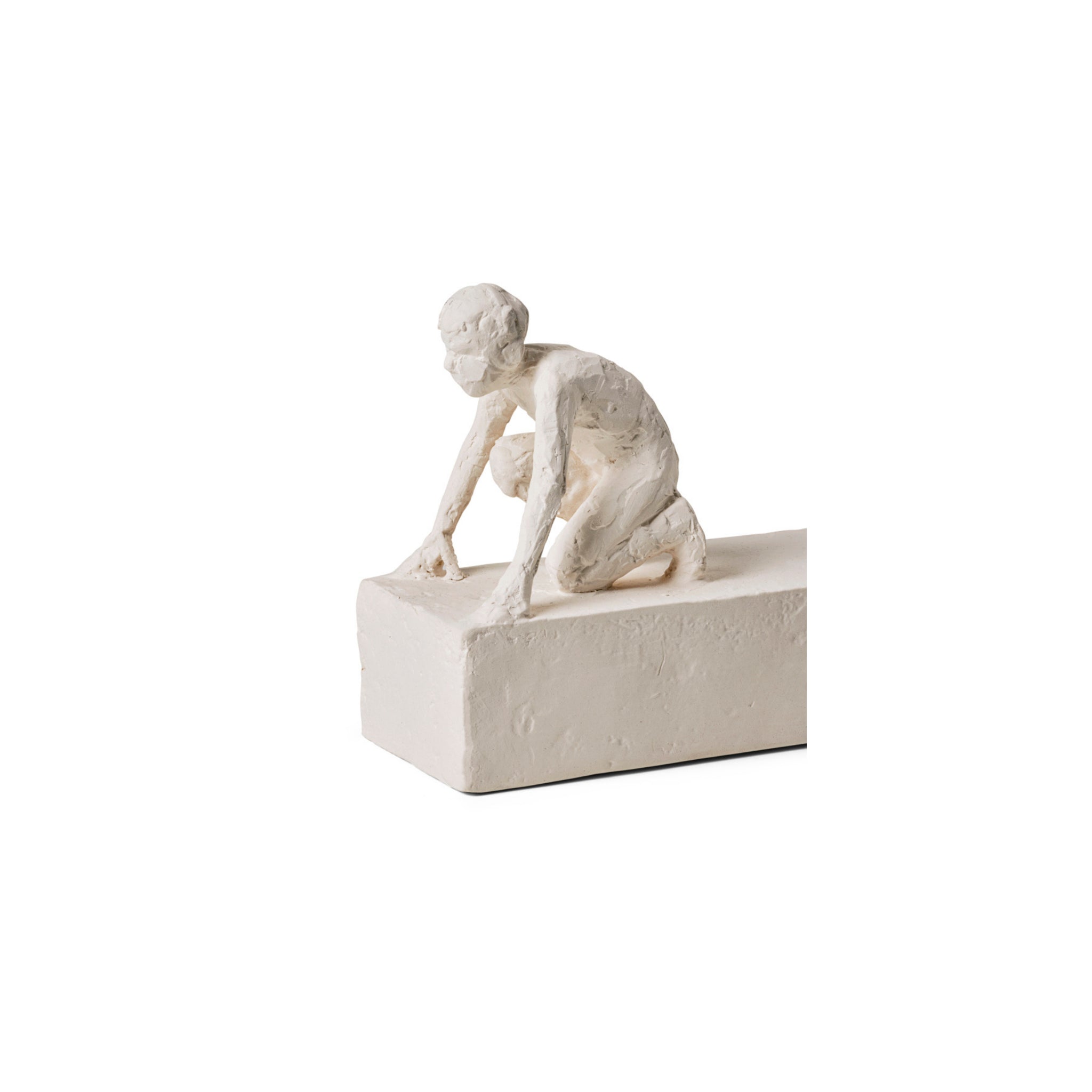De Kähler Astro Sterrenbeeld Sculptuur Ram van Kähler is een kleine, witte sculptuur van een gehurkte menselijke figuur met een ruwe textuur, geposeerd als een hardloper die op het punt staat te sprinten op een rechthoekig blok.