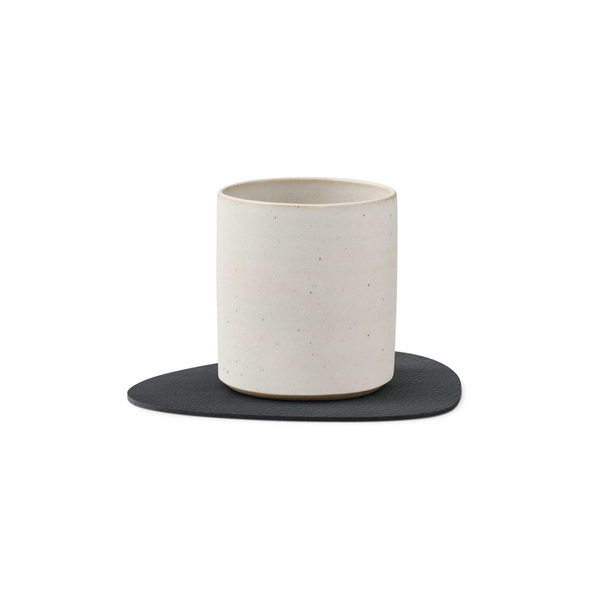 Een eenvoudige, cilindervormige beker van gebroken wit keramiek rust op een Lind DNA Serene Onderzetter Curve Antraciet 11/13, met een textuur van gerecycled leer, tegen een witte achtergrond.