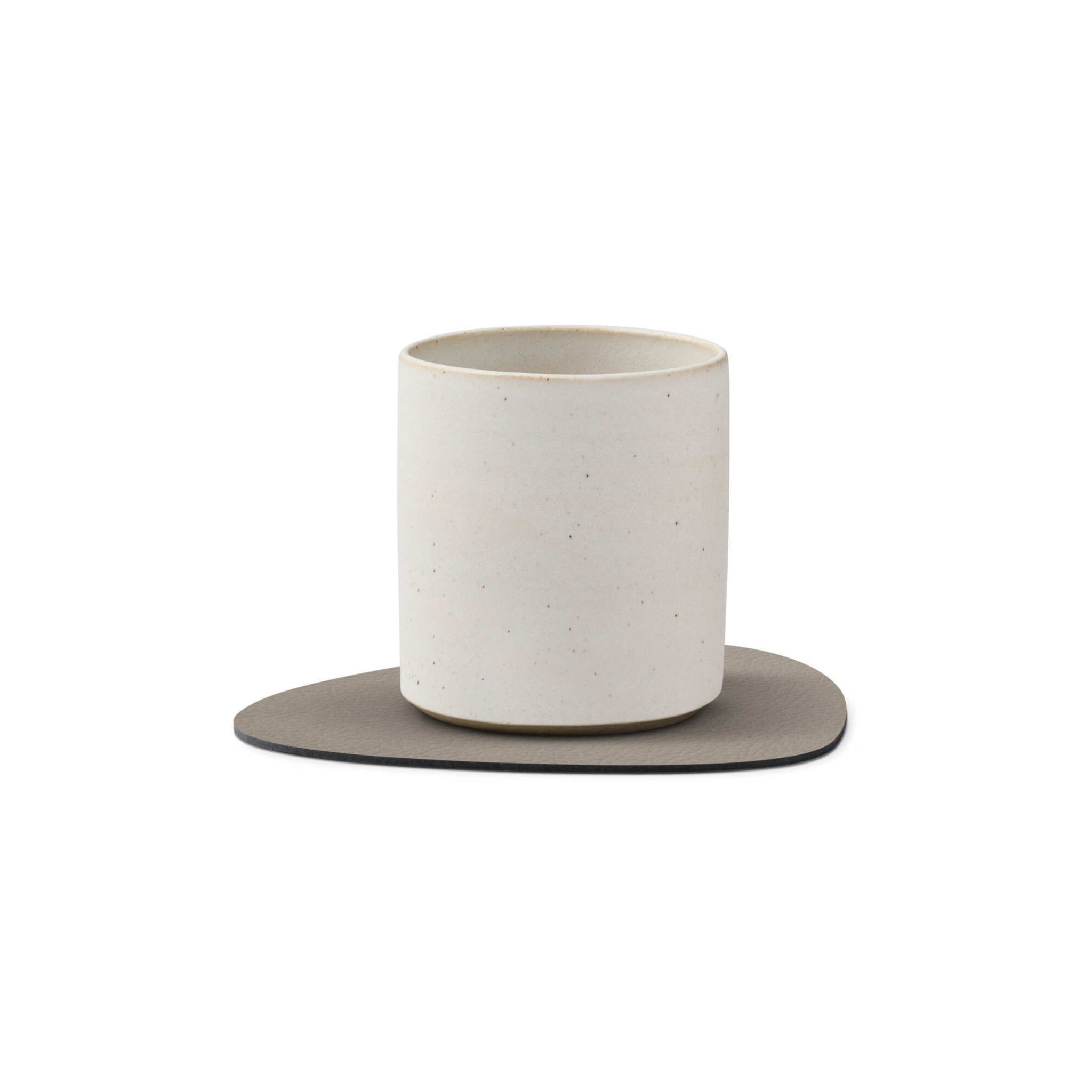 Op de Lind DNA Serene Onderzetter Curve Ash 11/13 rust een minimalistische beker van gebroken wit keramiek met gerecyclede leertextuur tegen een effen witte achtergrond.