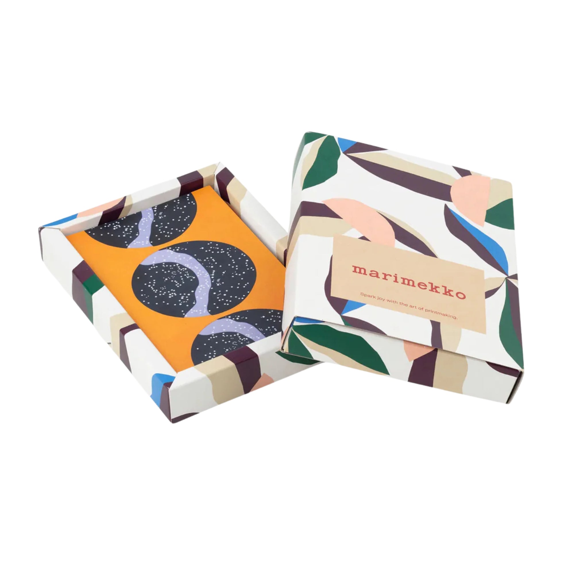 Een gedeeltelijk geopende Marimekko Postkaarten 50 st. doos toont een gevouwen ansichtkaart met een opvallende cirkelvormige afbeelding op oranje - ideaal voor liefhebbers van Scandinavisch design.