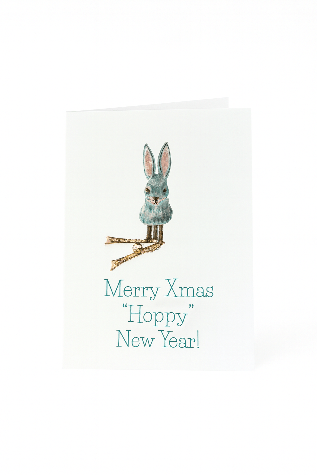 Op de Matriks Kerst- en Nieuwjaarskaart Merry Christmas Hoppy New Year! van Matriks staat een blauw konijntje met roze oren en gouden pootjes boven de tekst "Merry Xmas Hoppy New Year!" op een effen witte achtergrond.