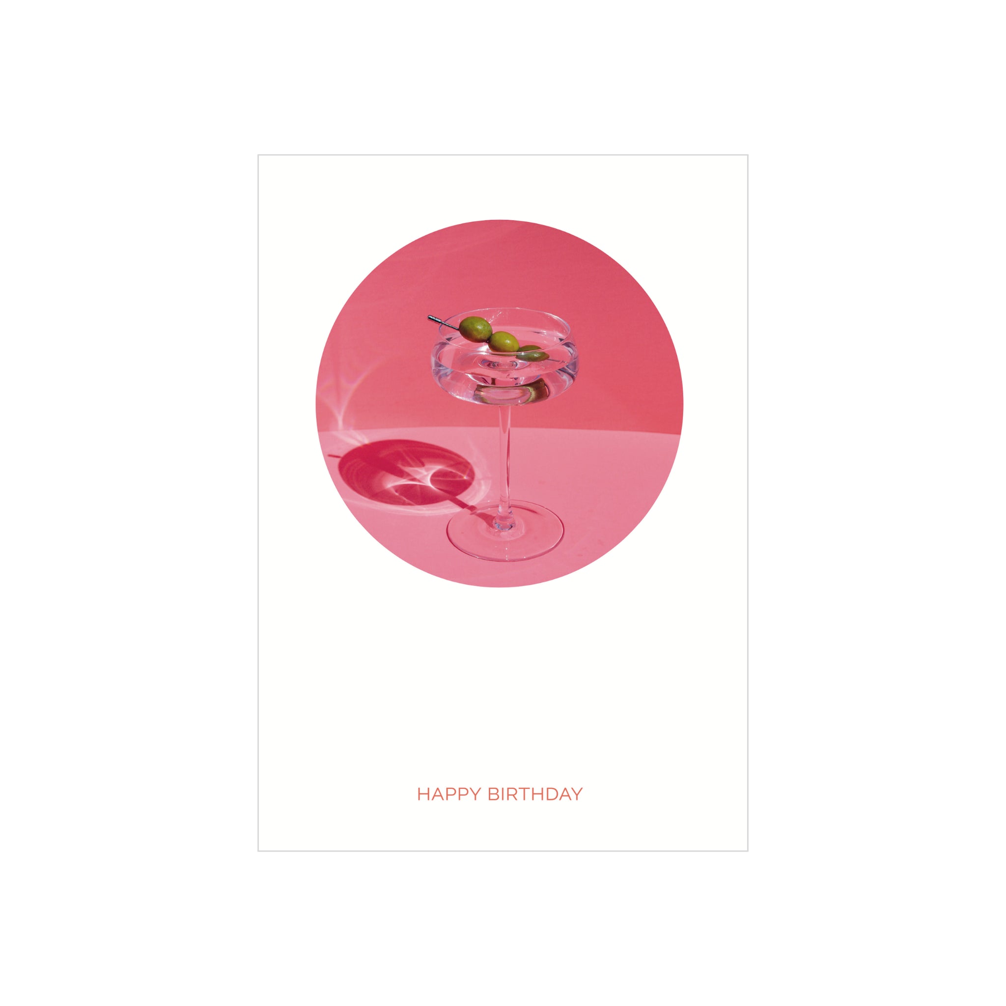 Een Matriks Postkaart Cirkel Happy Birthday Dubbel A6 toont een cocktailglas met drie olijven op een plectrum op een roze ondergrond, die een schaduw werpt. "HAPPY BIRTHDAY" in vet rood staat eronder - perfect voor unieke wenskaarten van het merk Matriks.
