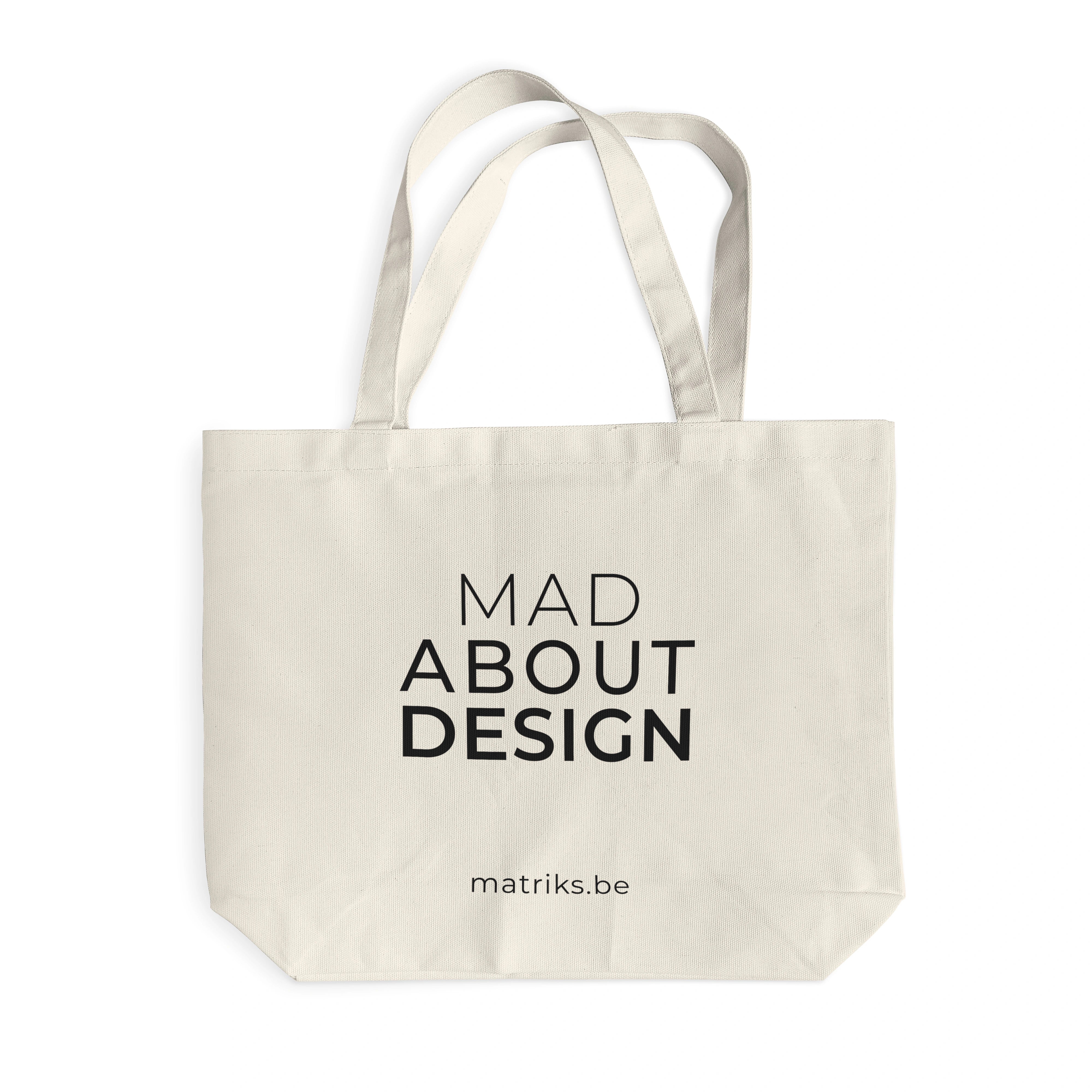 De Matriks Mad About Design Tote Bag van Matriks is een beige canvas tas van duurzaam materiaal, met "MAD ABOUT DESIGN" in zwart en matriks.be eronder - een must-have voor elke designliefhebber, afgebeeld op een witte achtergrond.