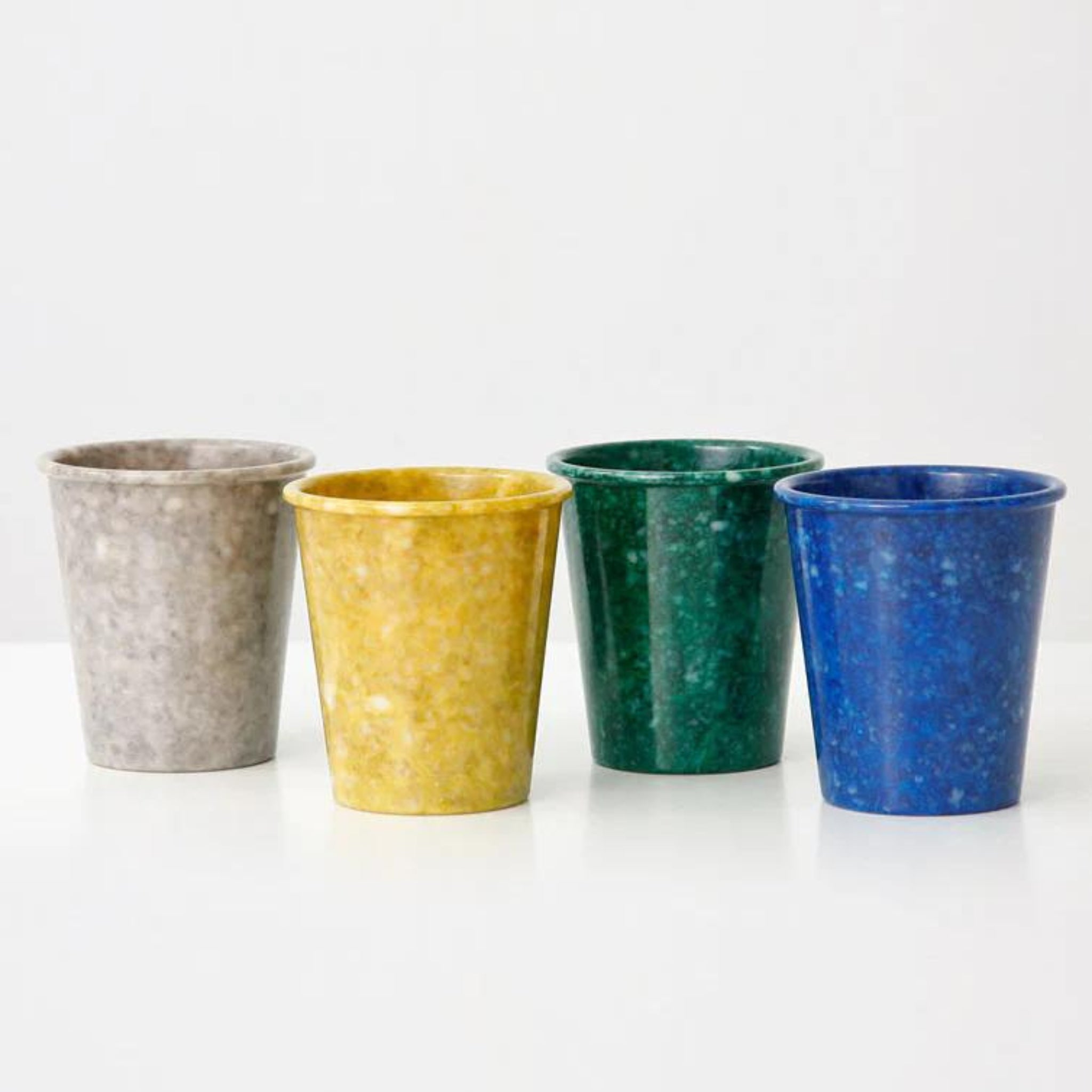 De Melamine Marbled Beker Mosterd van Melamine Marbled is gerangschikt op een wit oppervlak - ideaal als stijlvol badkamer accessoire of bureau organizer.