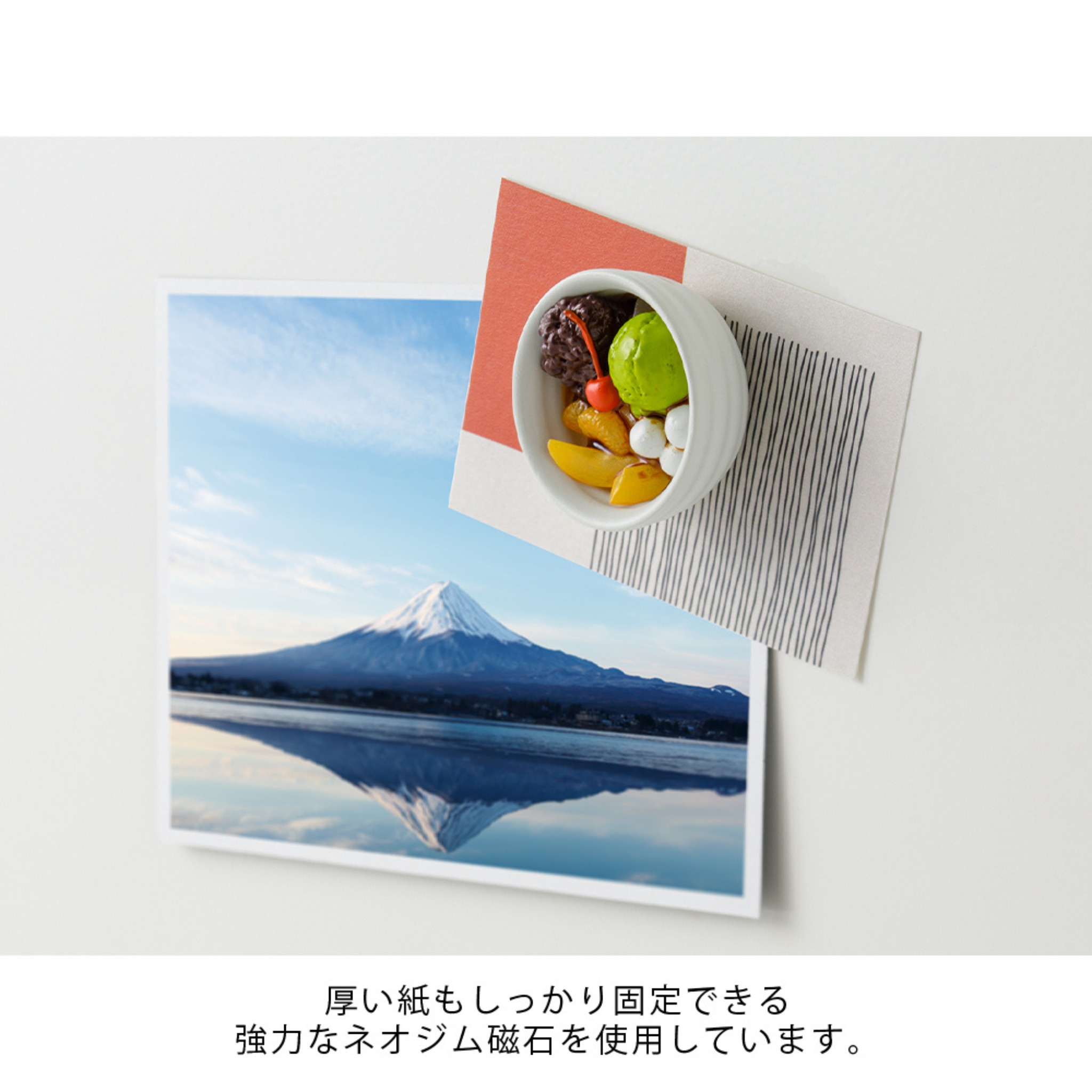 Een foto van de berg Fuji bij een meer is bevestigd op een wit vlak met een Midori Miniatuur Magneet. Daarnaast staan een schaaltje dat lijkt op de Midori Miniatuur Magneet Anmitsu en een roodgestreepte kaart, met Japanse tekst onder de afbeelding.