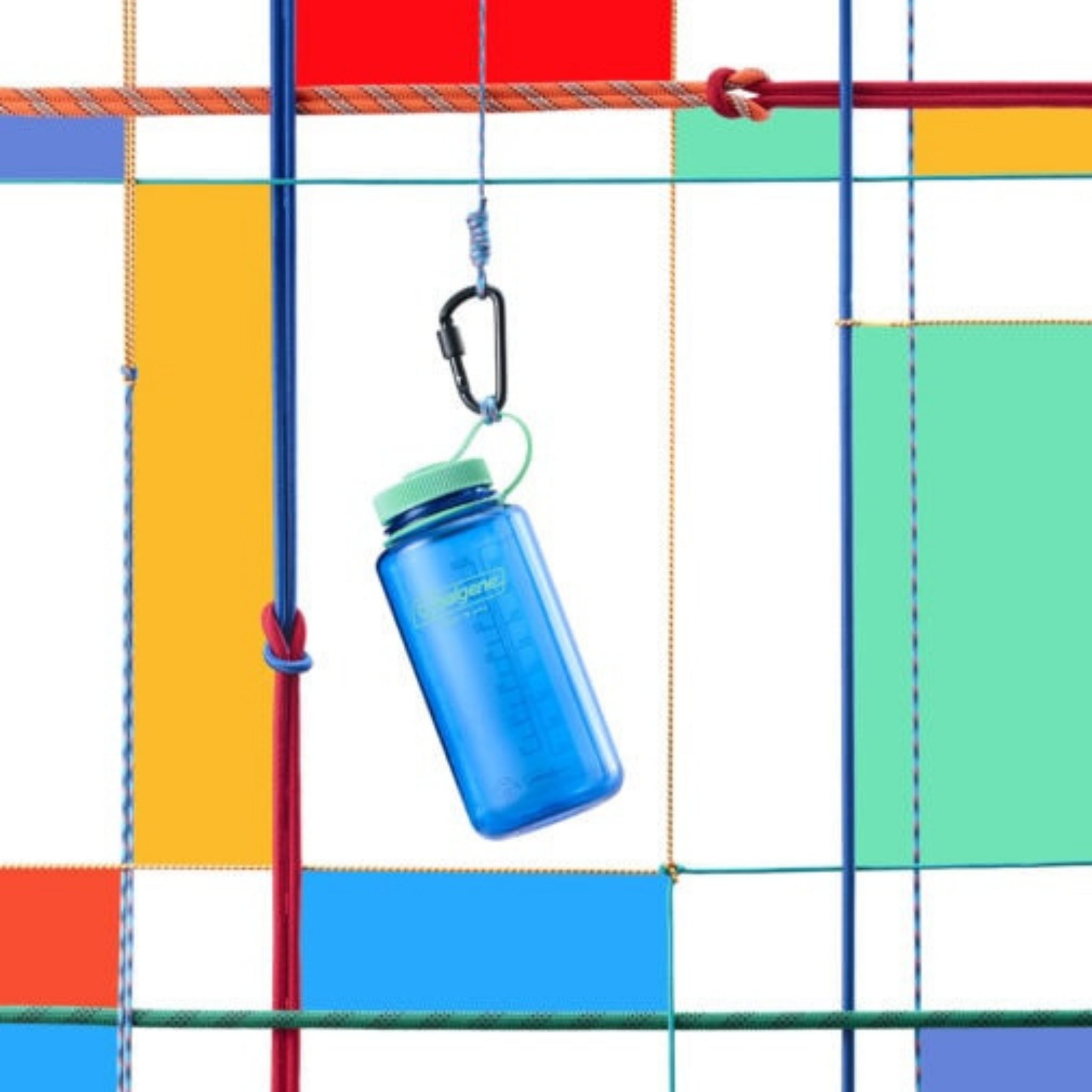 Een Nalgene Drinkfles Brede Opening Cornflower Blue 1L met een groene dop hangt aan een zwarte karabijnhaak, bevestigd aan een kleurrijk raster van touwen en geometrische vormen in rood, geel, blauw en oranje op een witte achtergrond.