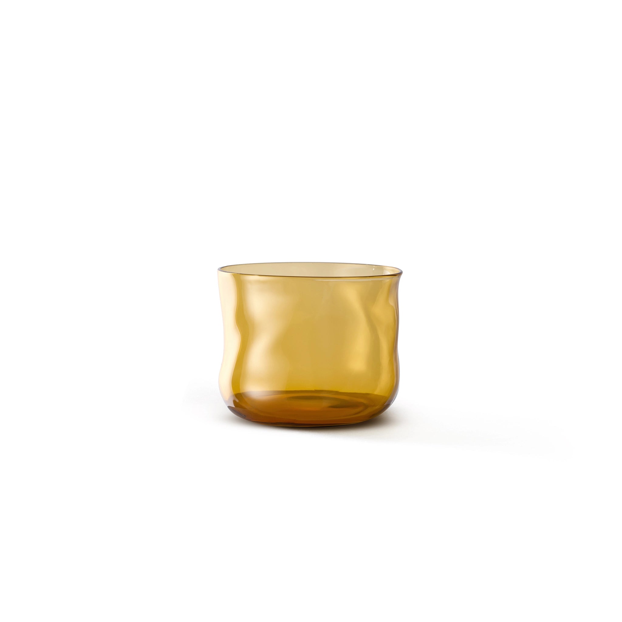 De Paveau Swirl Waterglas Dune Geel 24 cl, een kleine amberkleurige glazen beker van borosilicaatglas met een organische golvende vorm, staat elegant tegen een effen witte achtergrond.