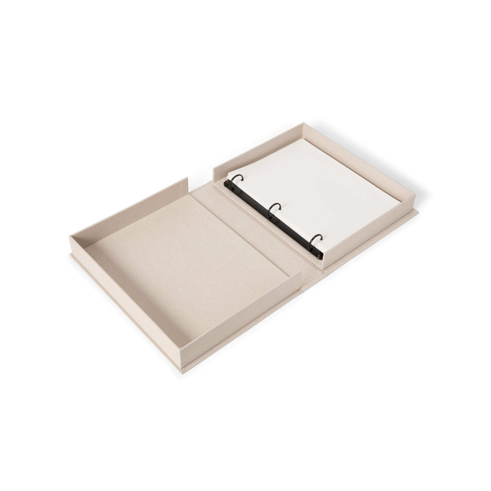 Een met beige stof bekleed Fotoalbum Moments that Matter the Most van Printworks ligt open op een salontafel en toont het album met drie ringen met lege witte pagina's aan de rechterkant en lege opbergruimte aan de linkerkant.