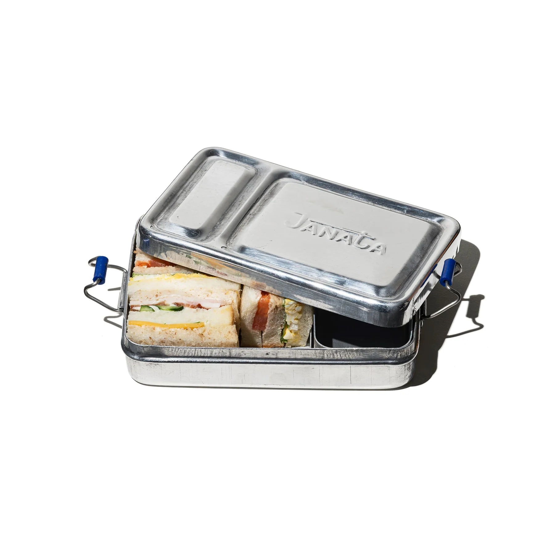 Een gedeeltelijk geopende aluminium lunchbox van Puebco toont broodjes met sla en ander beleg, geïsoleerd op een witte achtergrond.