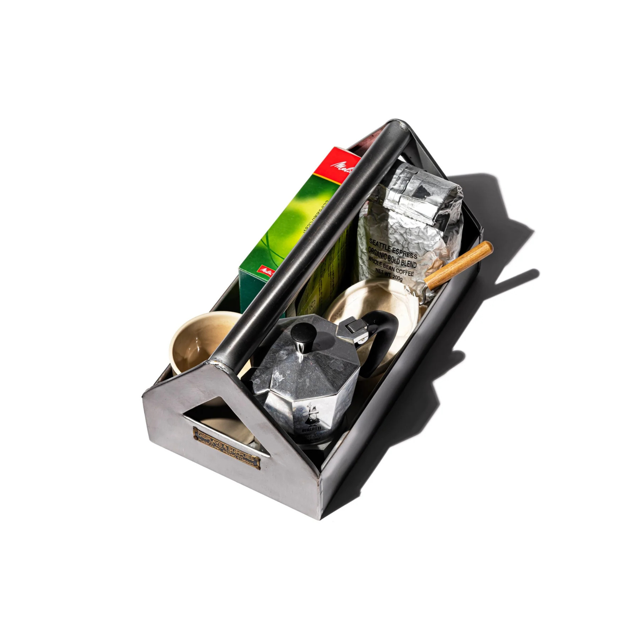 De Puebco Tool Organizer van Puebco bevat een mokapot, een koffiepakket, een groene doos, twee koperen kopjes en een kleine lepel met houten handvat, allemaal netjes gerangschikt tegen een witte achtergrond met een subtiele schaduw.