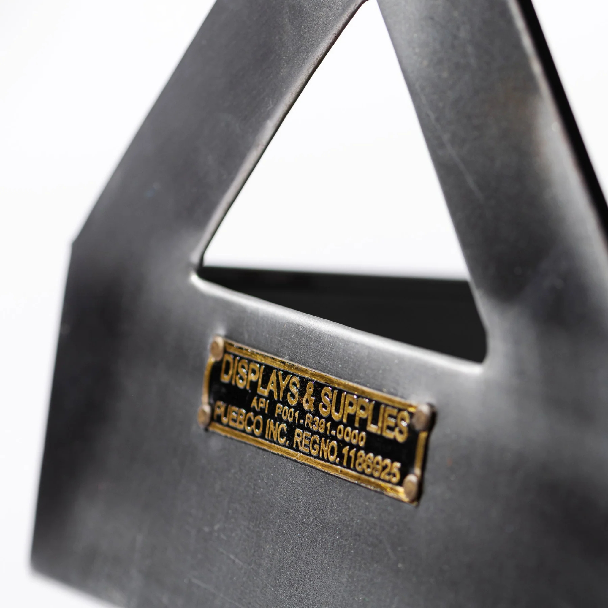 Een close-up van de Puebco Tool Organizer van Puebco, met een driehoekige uitsparing en een koperen label met de tekst "DISPLAYS & SUPPLIES", tegen een onscherpe witte achtergrond.