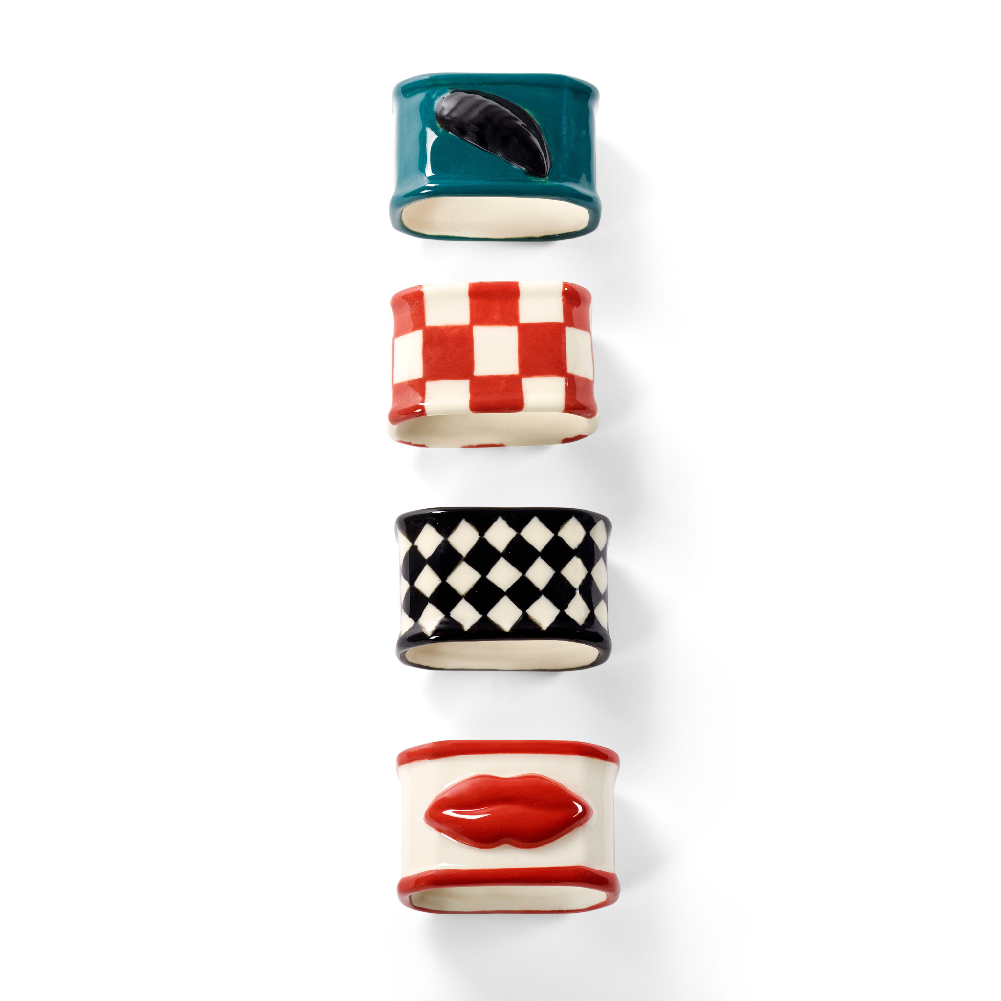 De Serax Wouters & Hendrix Servetring 4 st. set van Serax heeft vier servetringen van keramiek in opvallende designs: groenblauw met zwarte bladeren, rood-witte ruiten, zwart-witte diamanten en een motief van rode lippen.
