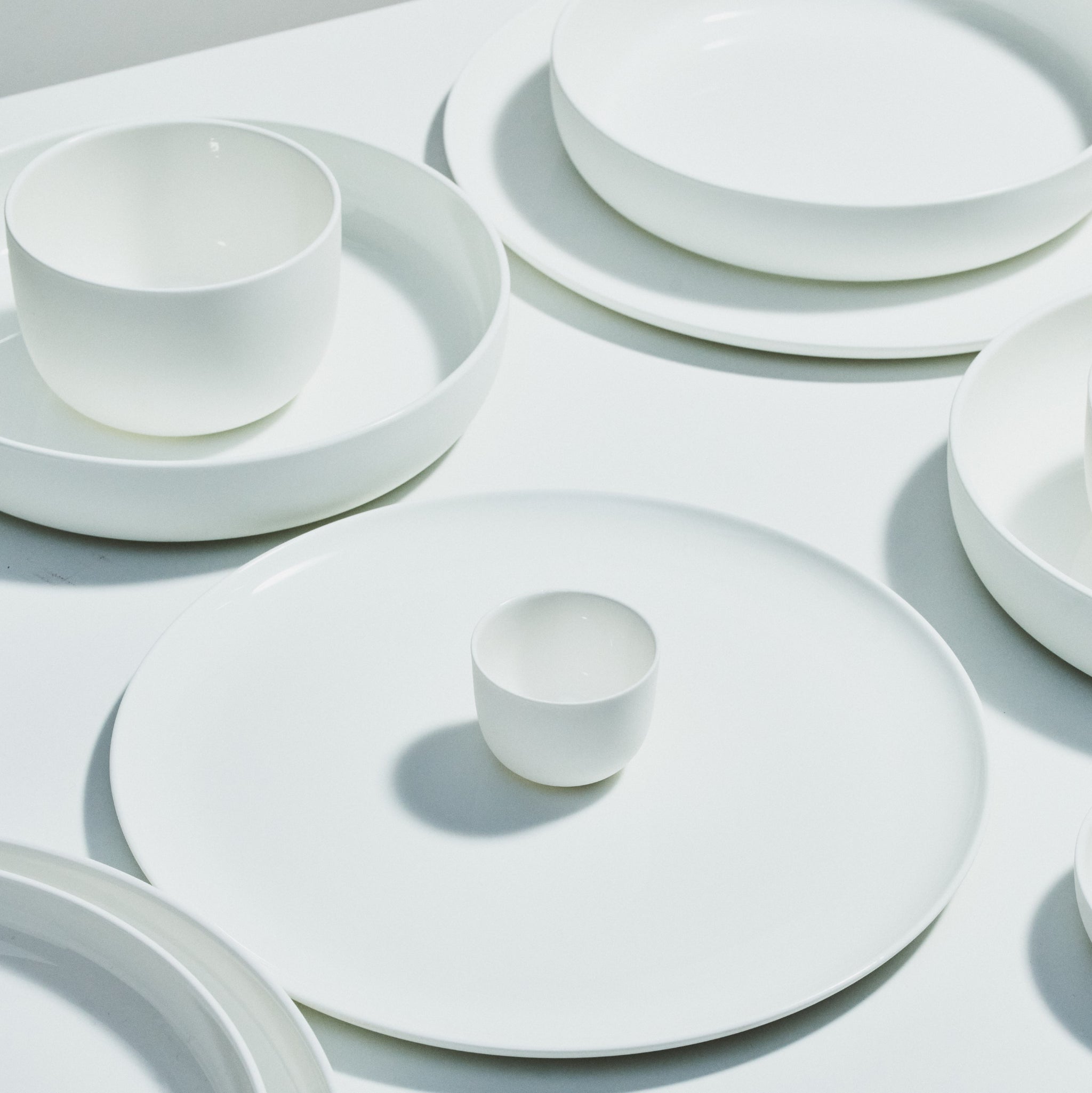 Een Serax Base Diep Bord D24 diep bord van Serax rust op een wit oppervlak en vormt een minimalistisch en modern tafereel met zachte schaduwen.