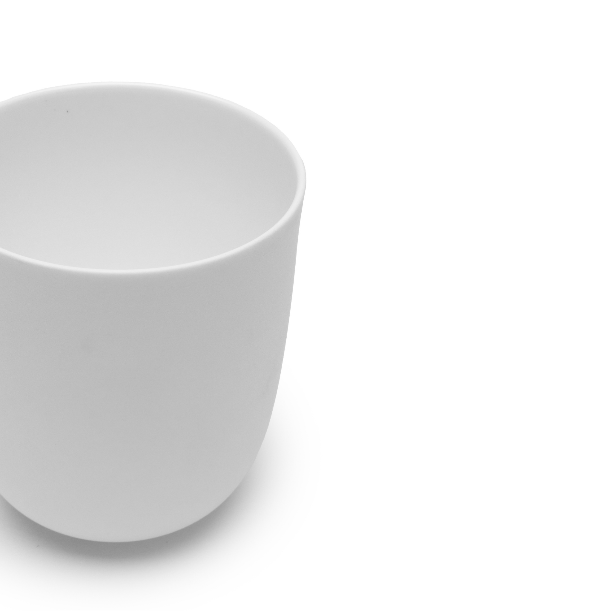 Een Serax Base Theekop zonder Oor 35 cl van Serax, gemaakt van wit Chinees porselein, is afgebeeld op een witte achtergrond met de linkerkant van de beker uitgesneden.