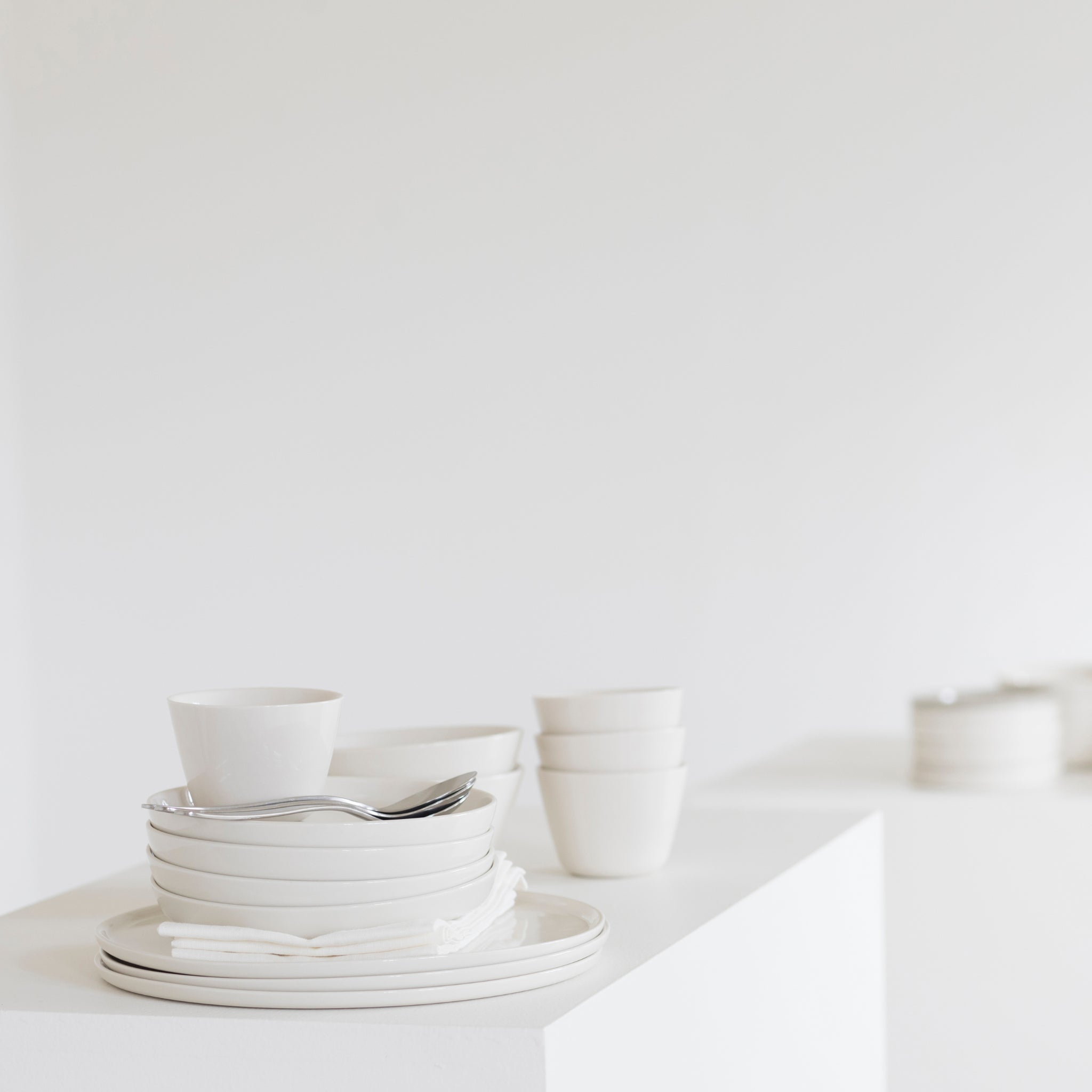 Een Serax Cena Laag Bord Ivoor D26 van Serax staat netjes op een witte sokkel tegen een effen witte achtergrond, wat zorgt voor een minimalistische en strakke esthetiek.