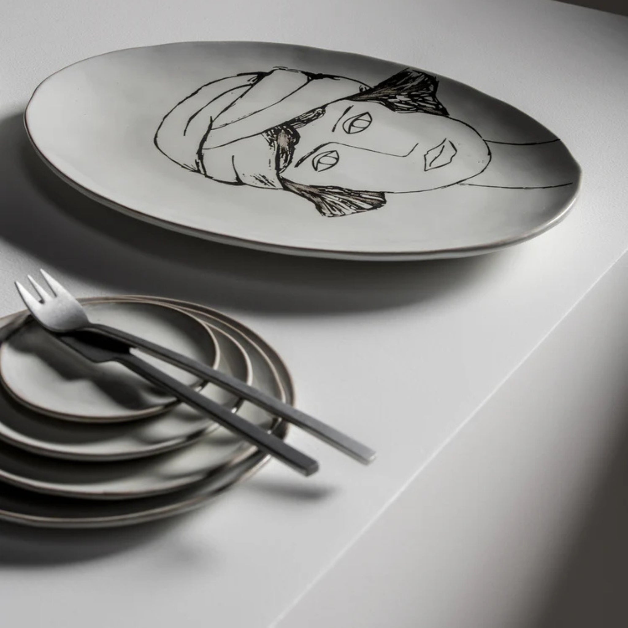 De Serax La Mère Laag Bord Wit D14,5 van Serax heeft een minimalistische elegantie met zijn strakke ontwerp, perfect om te combineren met kleine borden en dessertvorkjes voor een moderne tafelsetting.