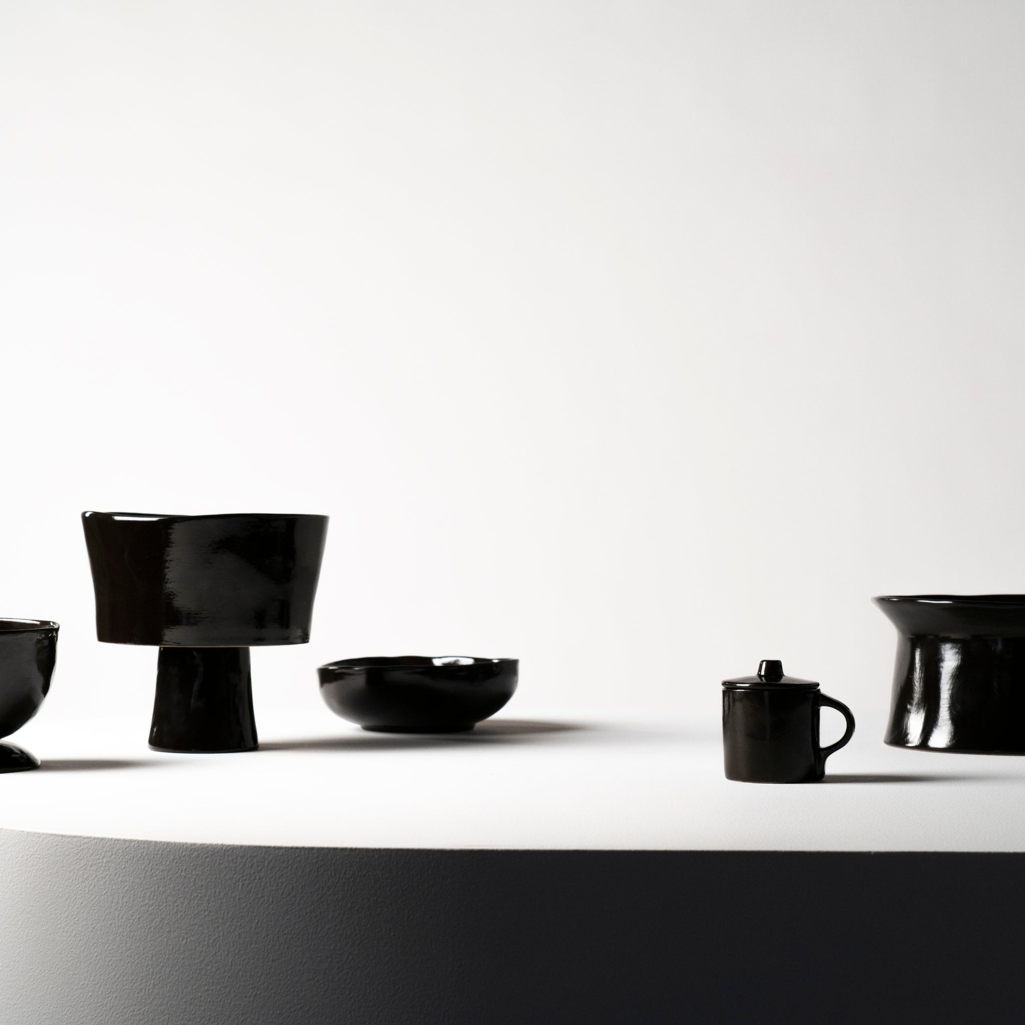 De Serax La Mère Taartschaal Ebony D30 van Serax wordt weergegeven op een rond wit oppervlak tegen een effen lichte achtergrond, waardoor de glanzende afwerking en het minimalistische ontwerp worden benadrukt.