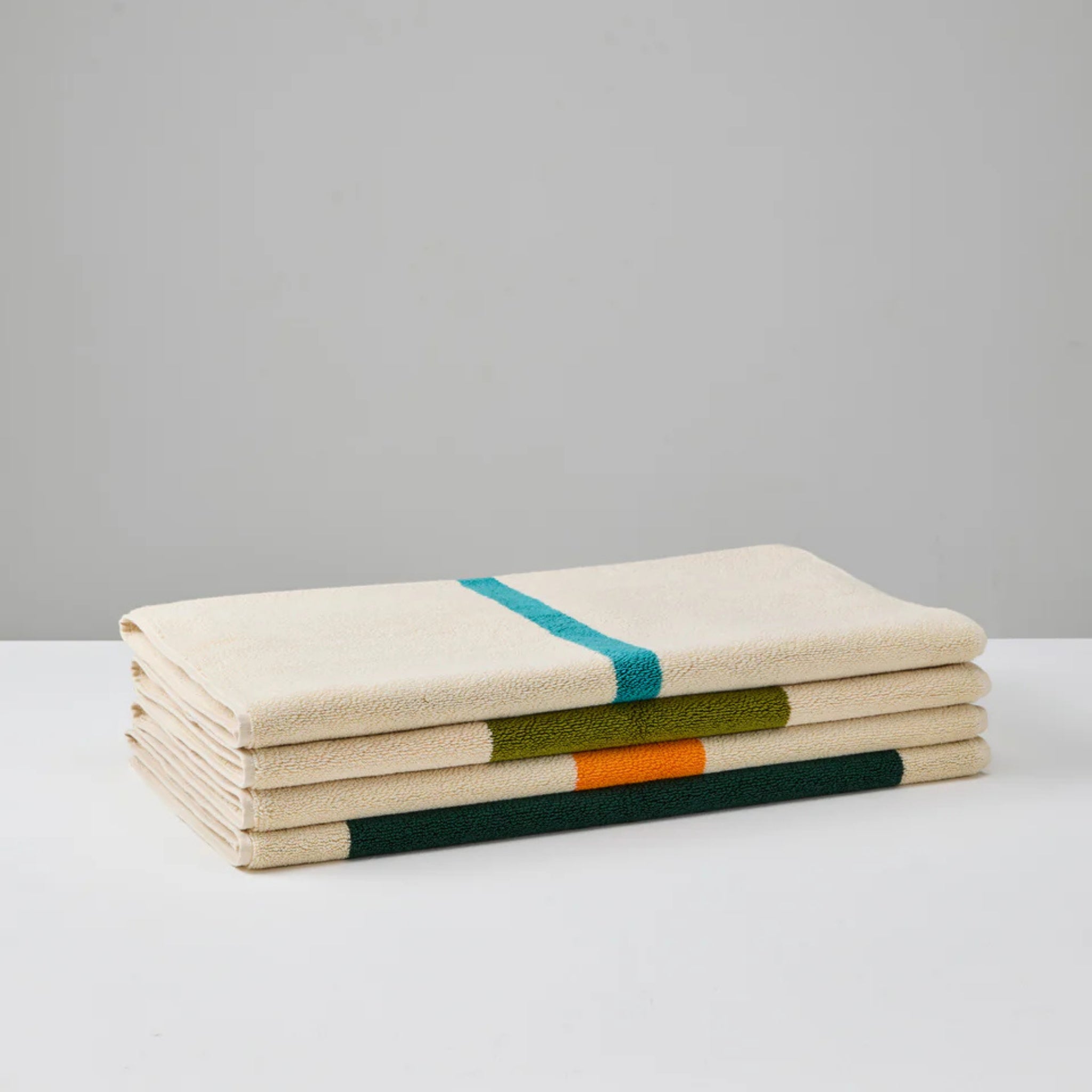 De Suite 702 Badmat Aqua Donkergroen 50/80 wordt gevouwen weergegeven op een wit oppervlak met een rijke donkergroene tint die afsteekt tegen een effen grijze achtergrond.