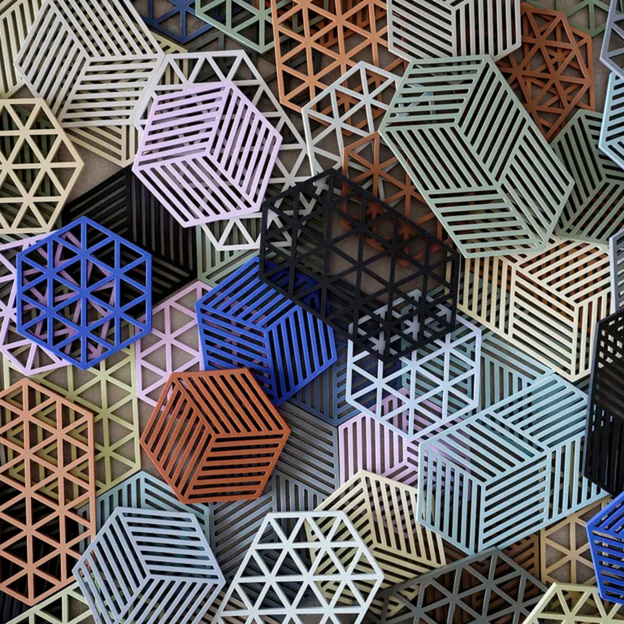 Een dichte opstelling van geometrische 3D-kubussen en zeshoeken in verschillende kleuren, met streep- en rasterpatronen - perfect als een moderne tafelaccessoire of de Zone Denmark Triangles Trivet Indigo, gemaakt van hittebestendig silicone door Zone Denmark.